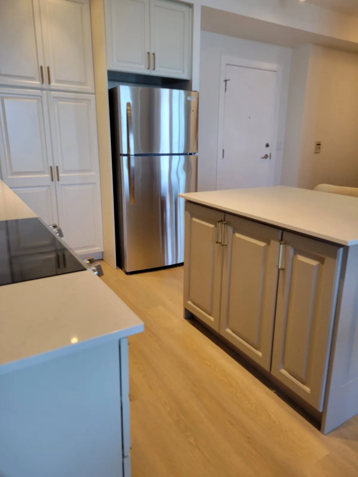 The finished island in a warm greige, standing against the cream tall cabinets and the stainless fridge behind it