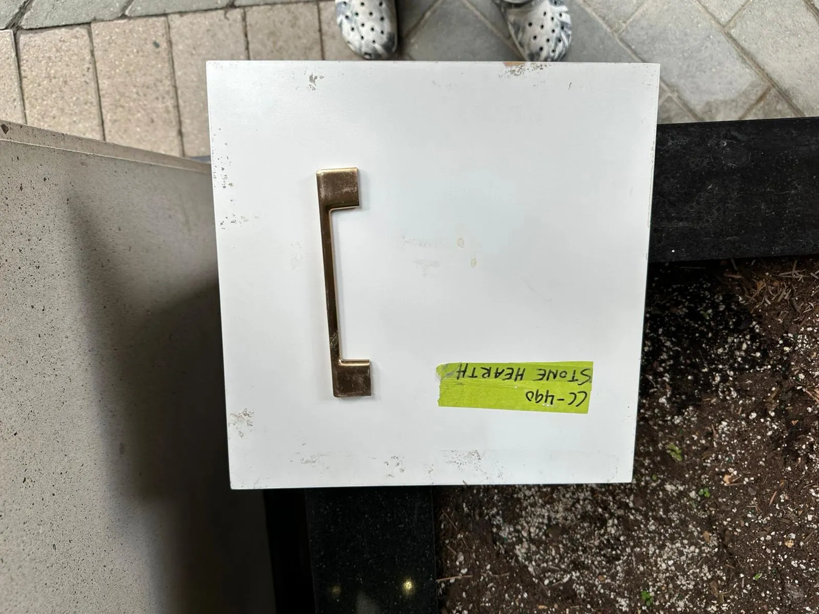 One finished door photographed at the shop, the new brass bar pull already fitted and a strip of tape on the face naming the colour