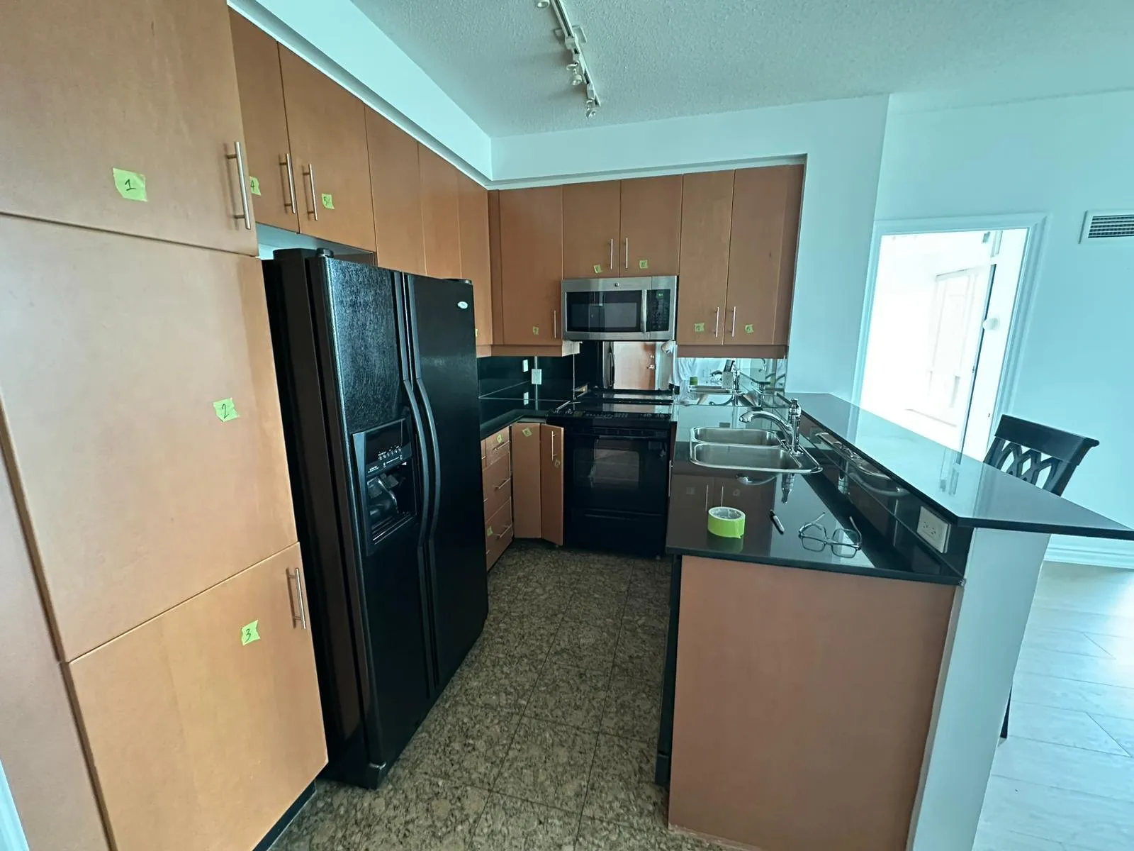 The kitchen before work started, orange-toned maple doors with numbered tape labels stuck to each one ready to come off