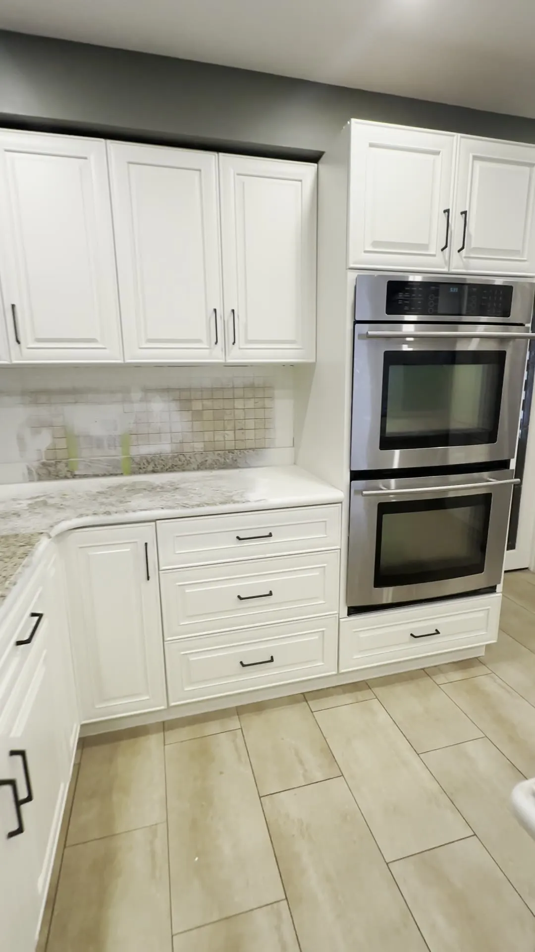 The finished East Credit kitchen — espresso cabinetry sprayed a warm cream around a peninsula and island, with the speckled granite counters and tile floor kept