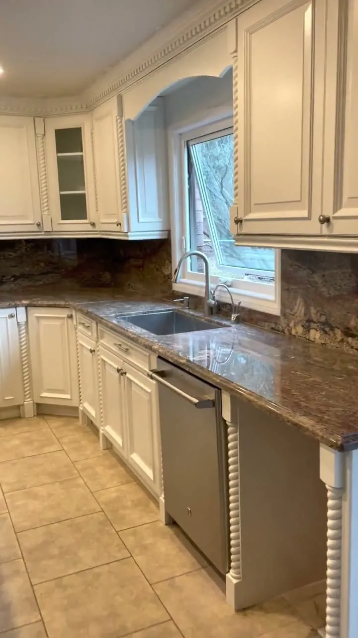 Walkthrough of the finished East Credit kitchen — espresso perimeter cabinetry sprayed a warm cream, island repainted a contrasting dark tone, granite counters and stone backsplash kept