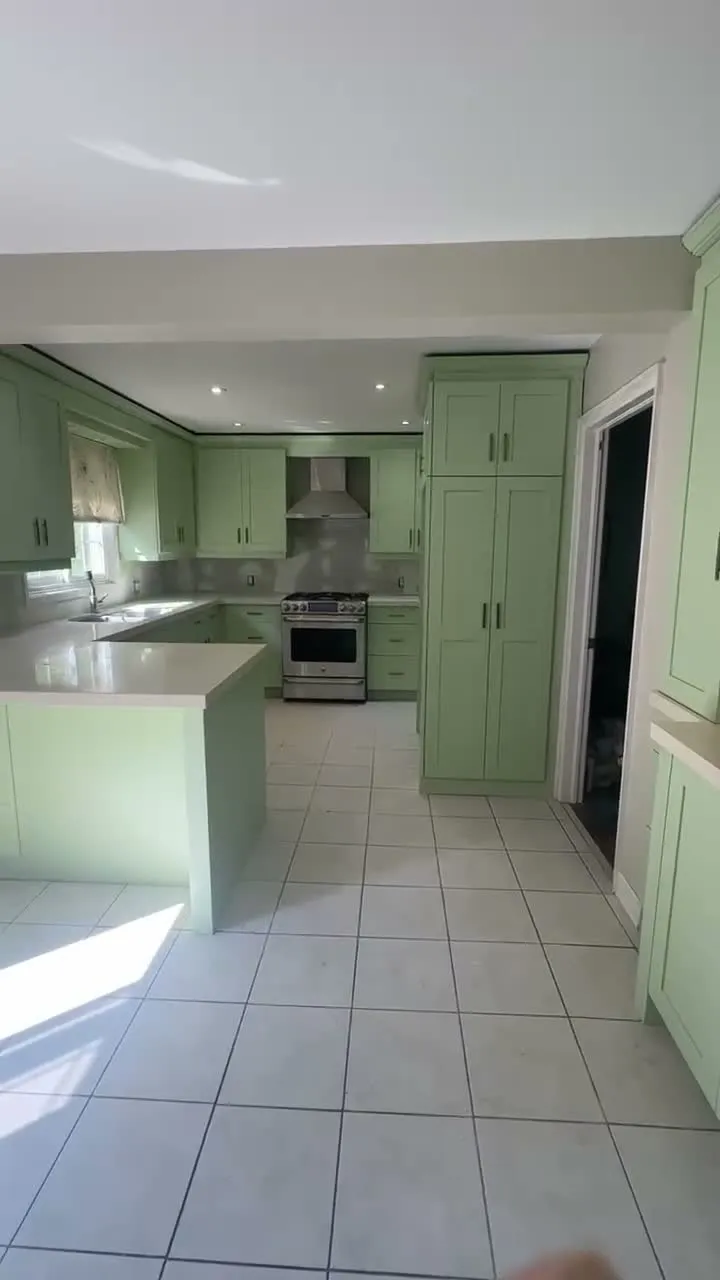 A walk through the Erin Mills kitchen with the doors back on — every door, drawer and frame in a soft light green, with the wall behind the counters still bare where the old tile came off