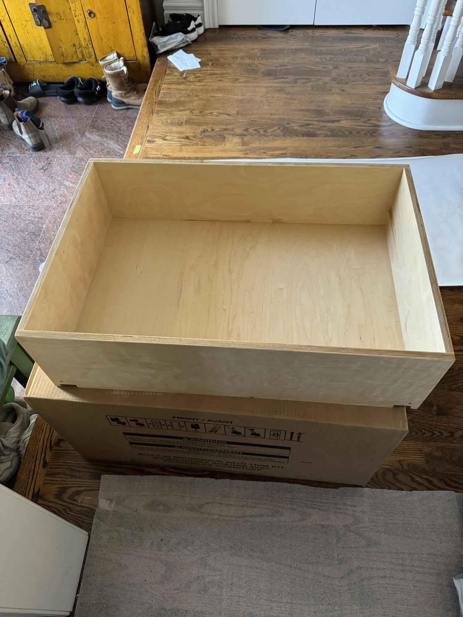 A new plywood drawer box built in the shop, standing on the floor beside its packaging