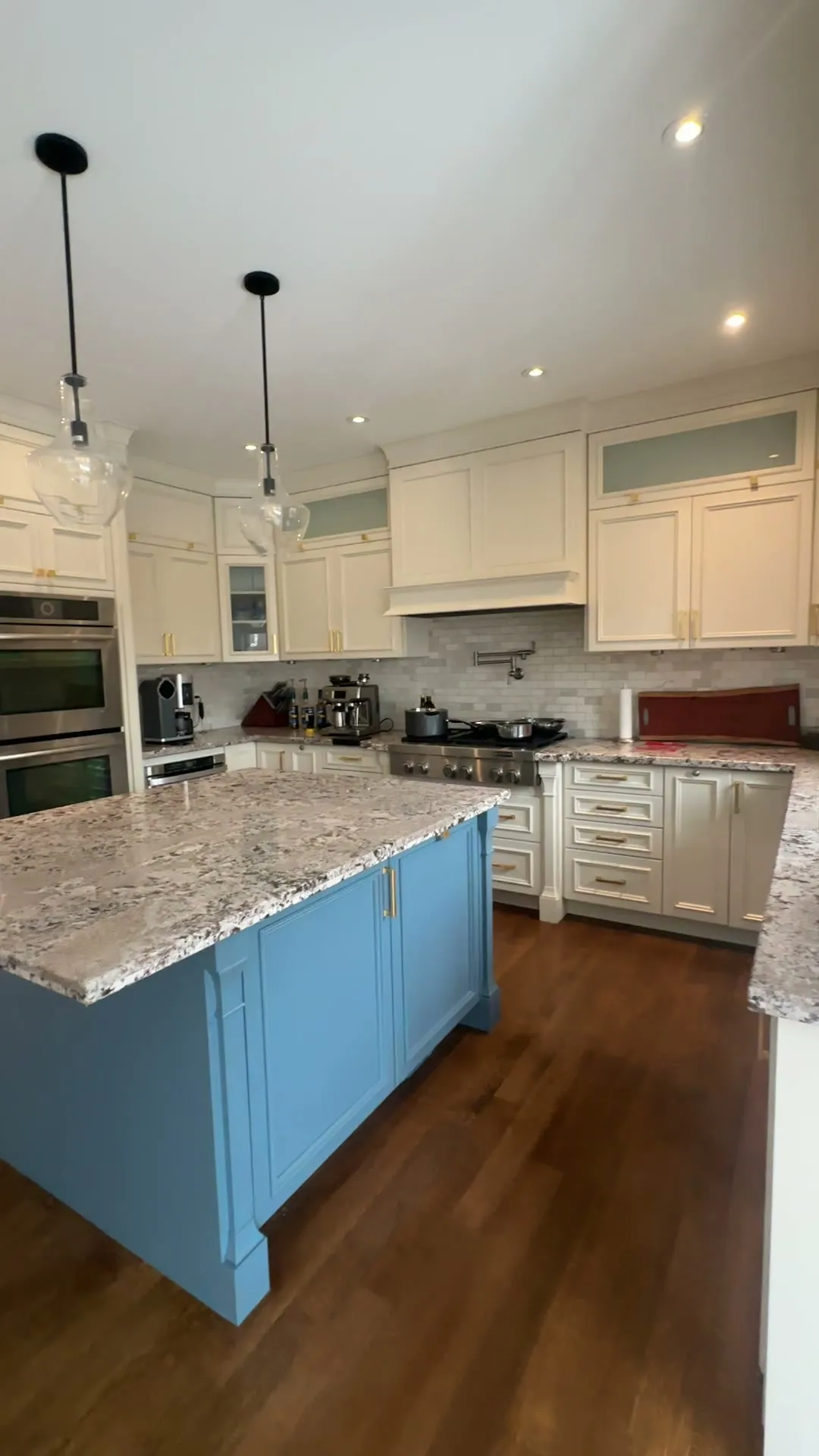 The Markham kitchen after the island was sprayed, walking from the fridge past the range to the blue island, the cream perimeter cabinets and brass handles either side