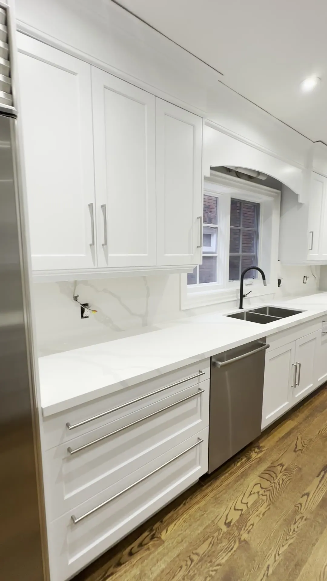 The finished Lawrence Park South kitchen — dark espresso cabinetry sprayed a soft off-white, with the hardwood floor and built-in appliances unchanged