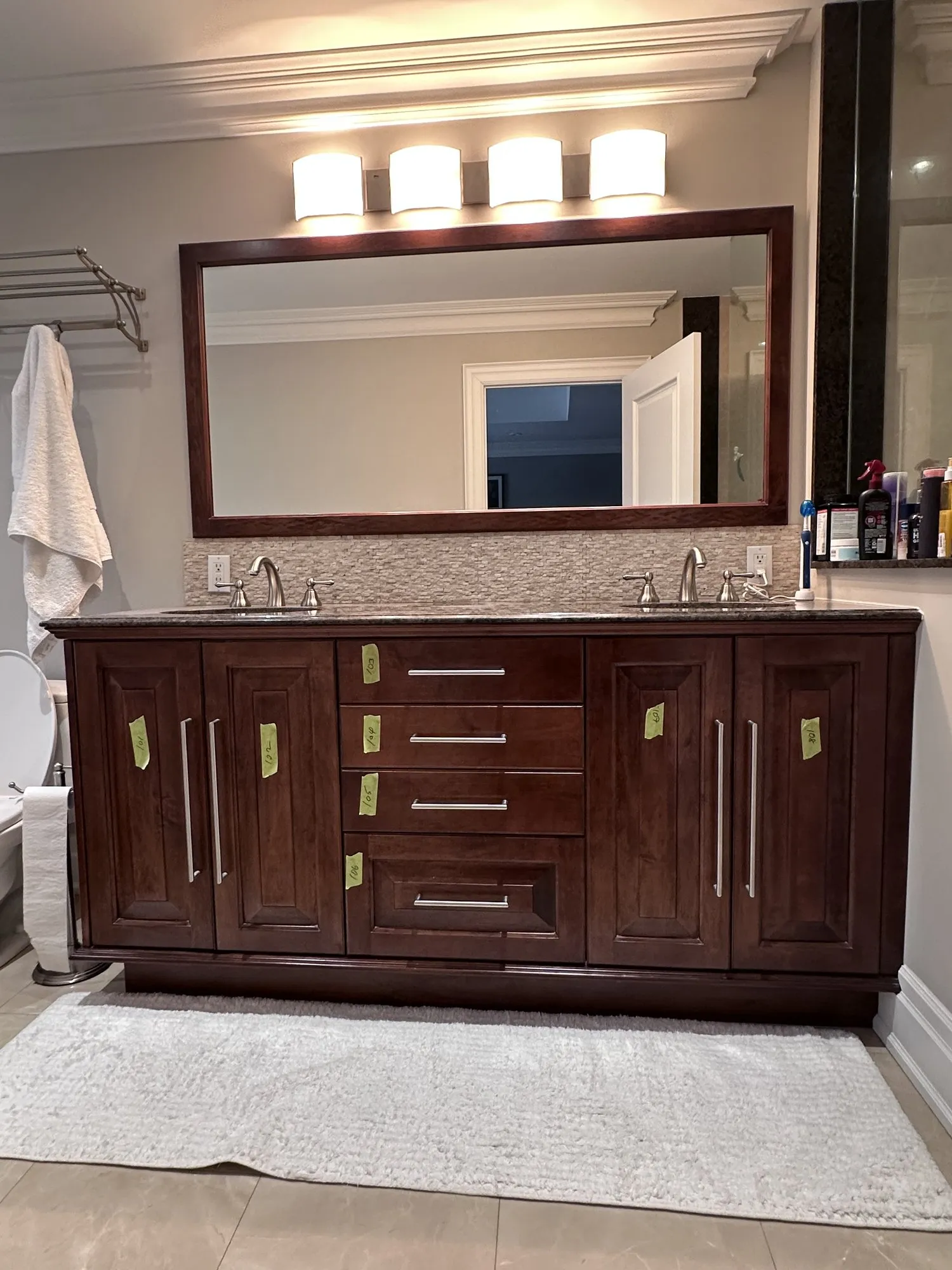 The master bathroom vanity before the work, a dark wood double vanity with a large mirror above it