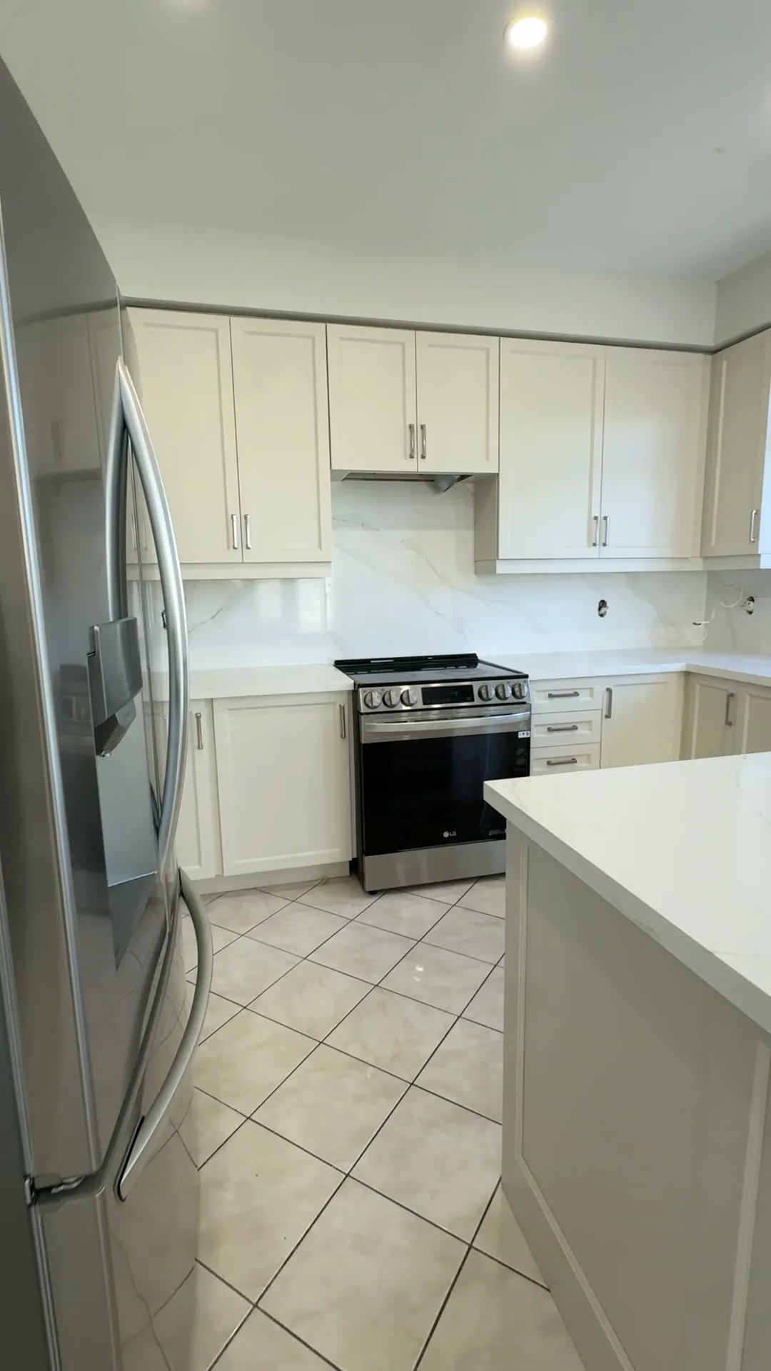 The finished Patterson kitchen — espresso cabinetry sprayed a soft cream, a rebuilt island under new quartz, and a new slab backsplash