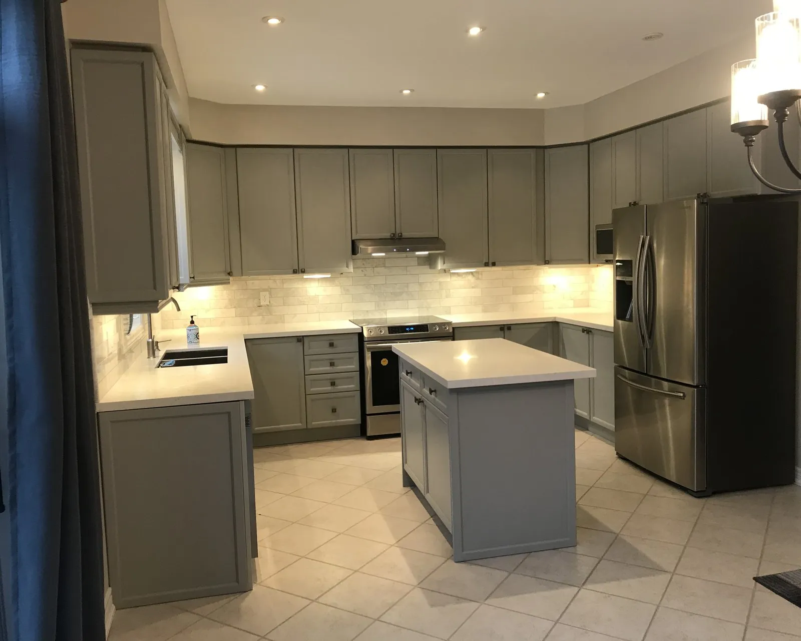 After — A kitchen before and after painting — oak fronts finished in a soft grey, with the island, the layout and the counters unchanged