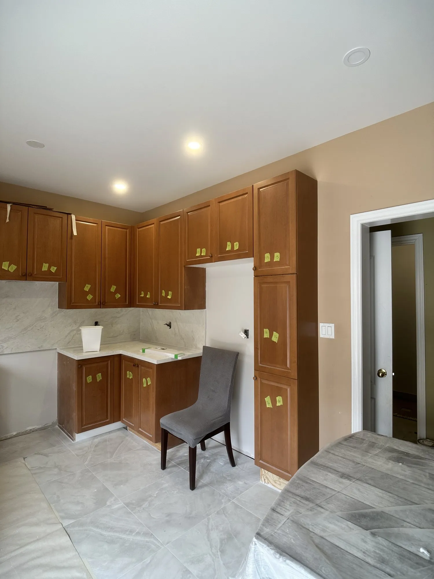 The original oak cabinets with a small green tag stuck to every door and drawer front before removal, the room already sheeted out