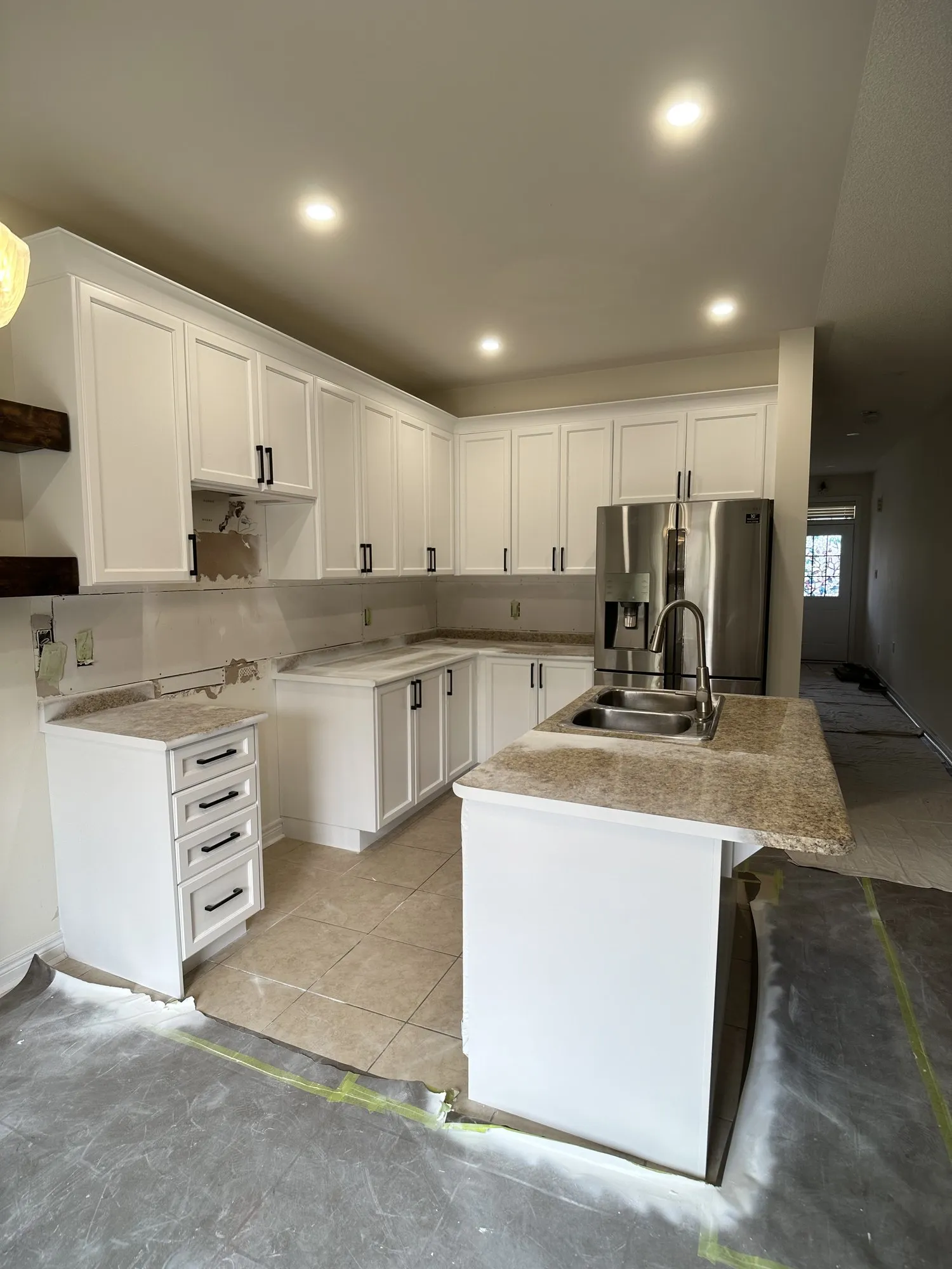 The finished kitchen with white cabinetry running to the ceiling, the original speckled granite counters and the rustic timber shelf both kept