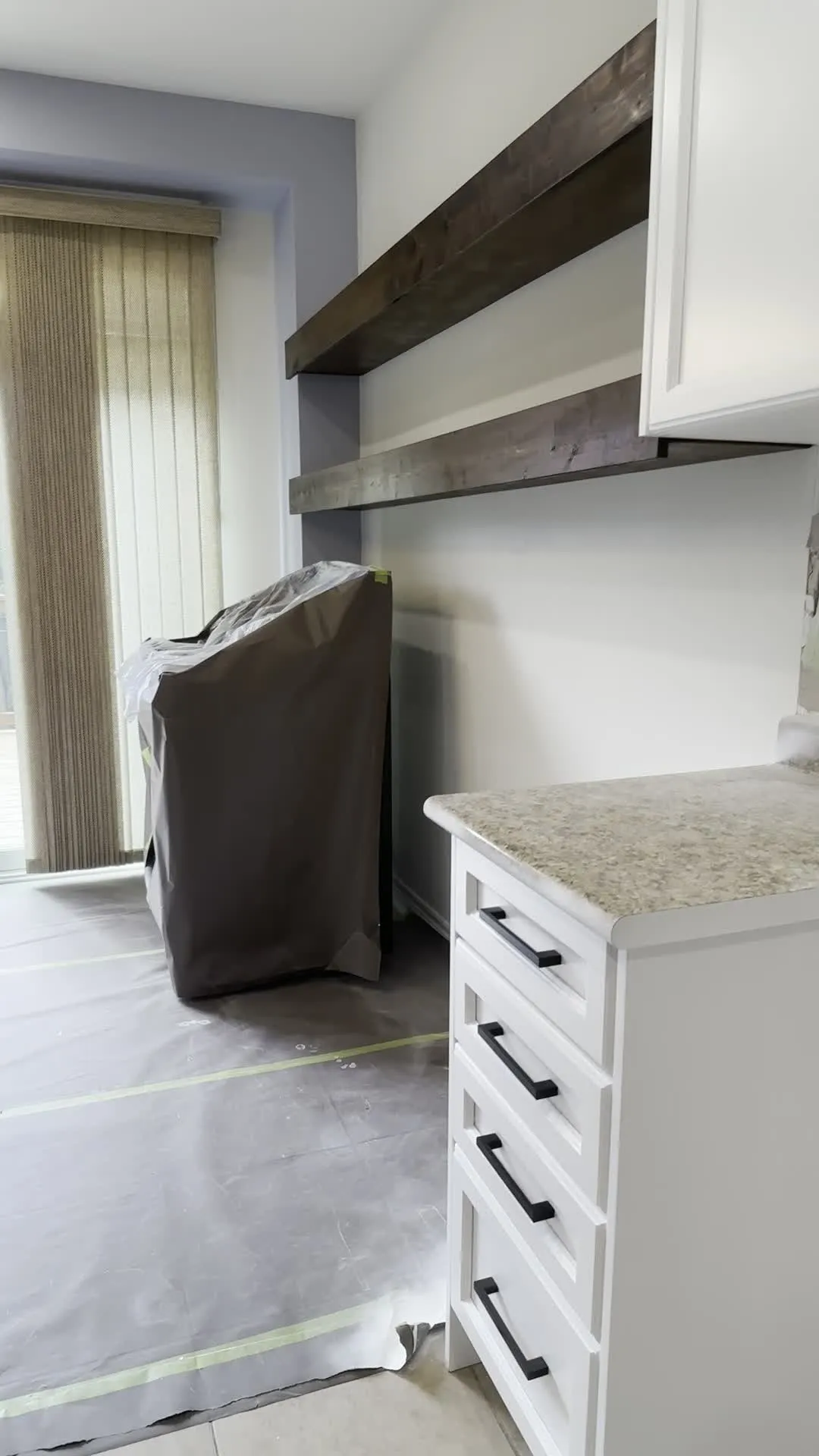 A walk through the finished Churchill Meadows kitchen — white cabinetry carried up to the ceiling on new crown moulding, with the original granite and the rustic timber shelf kept