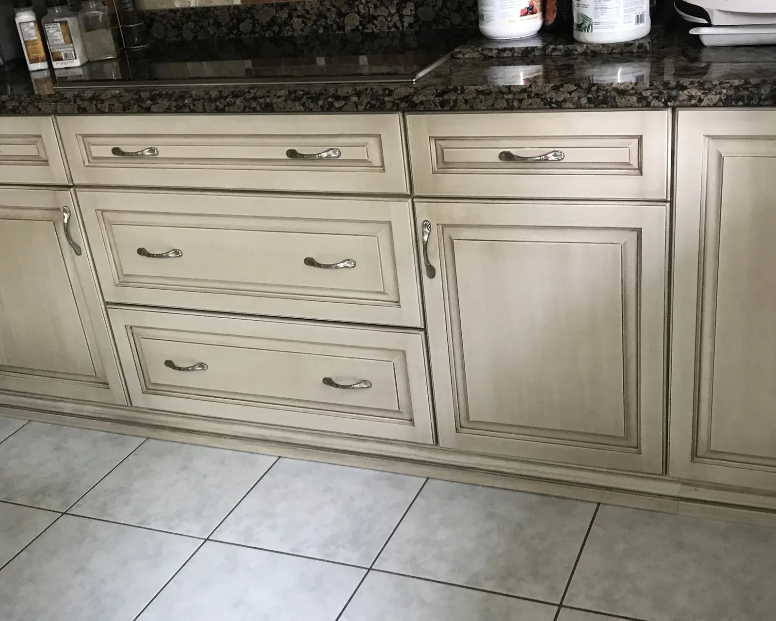 A run of refinished cabinet doors and drawer fronts, the glaze settled into the profile mouldings, under the original dark granite