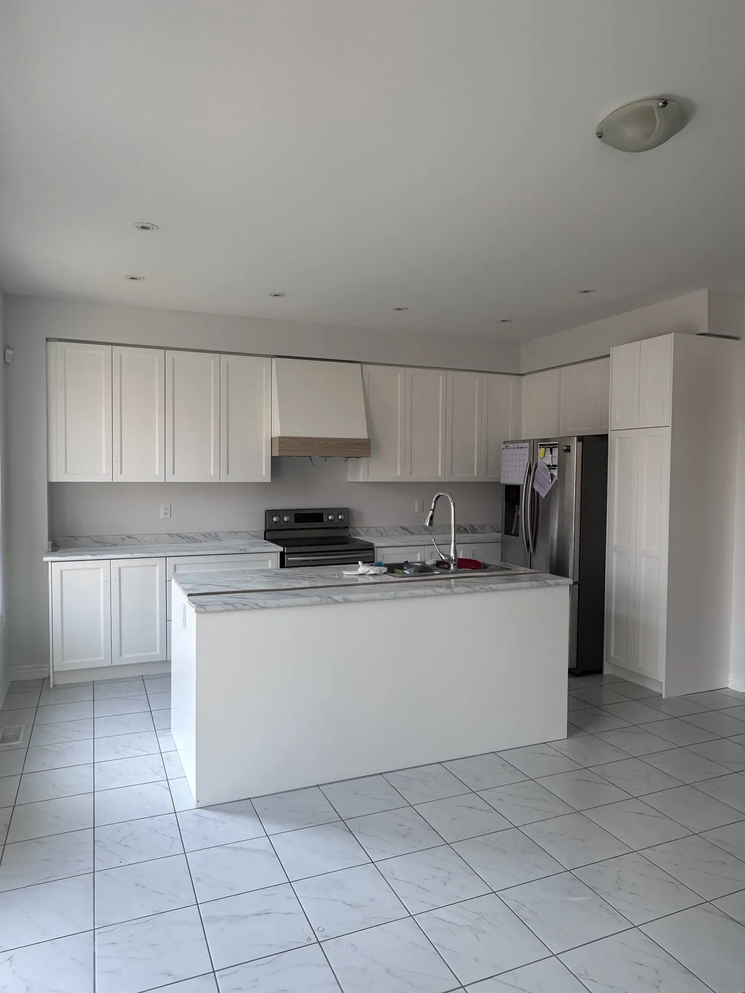 The finished kitchen with the new decorative hood box in place above the range, a band of natural timber across it against the off white cabinetry
