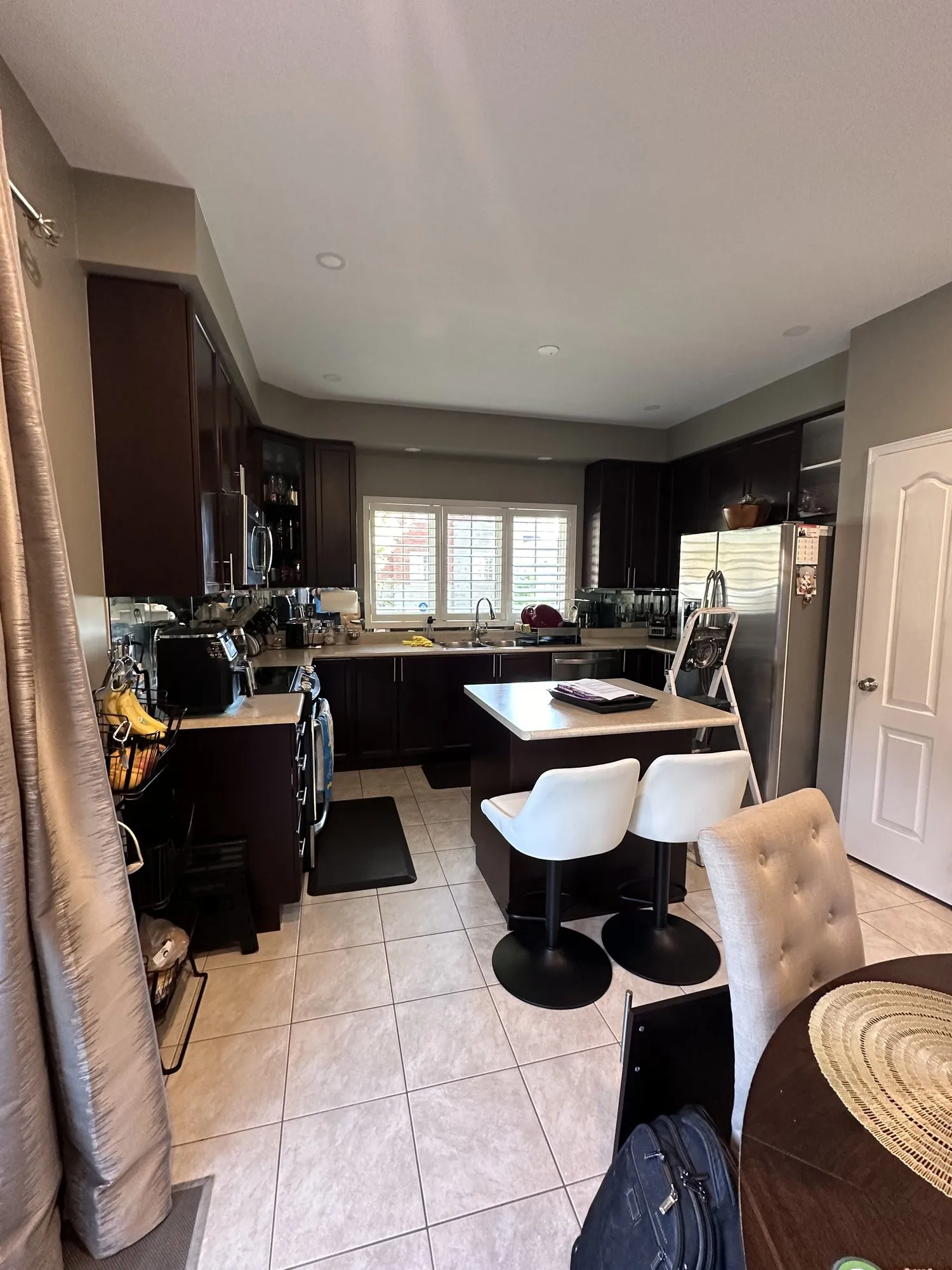 Before — Cabinet refinishing in Northeast Ajax — a dark espresso kitchen sprayed white, with the existing island extended by one cabinet under a single run of quartz
