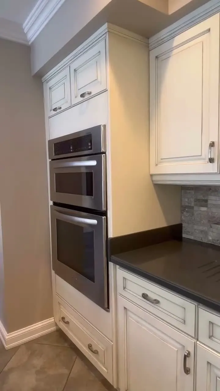 A walk through the finished Rosebank kitchen — cream glazed perimeter cabinetry against a dark island, with the new under-sink doors indistinguishable from the originals