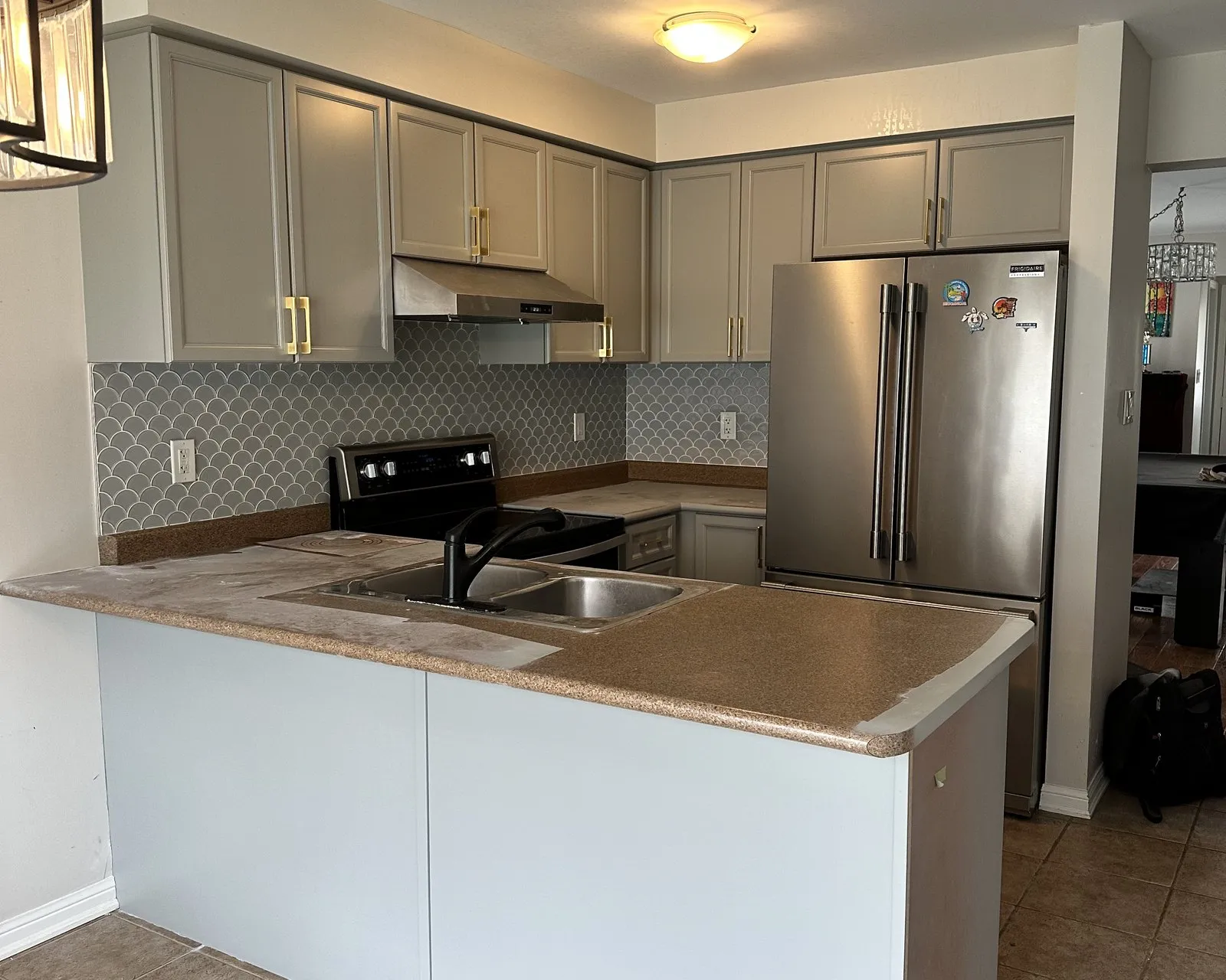 Before — The same kitchen before and after a countertop replacement — laminate tops swapped for white quartz with a waterfall end, the painted cabinets untouched