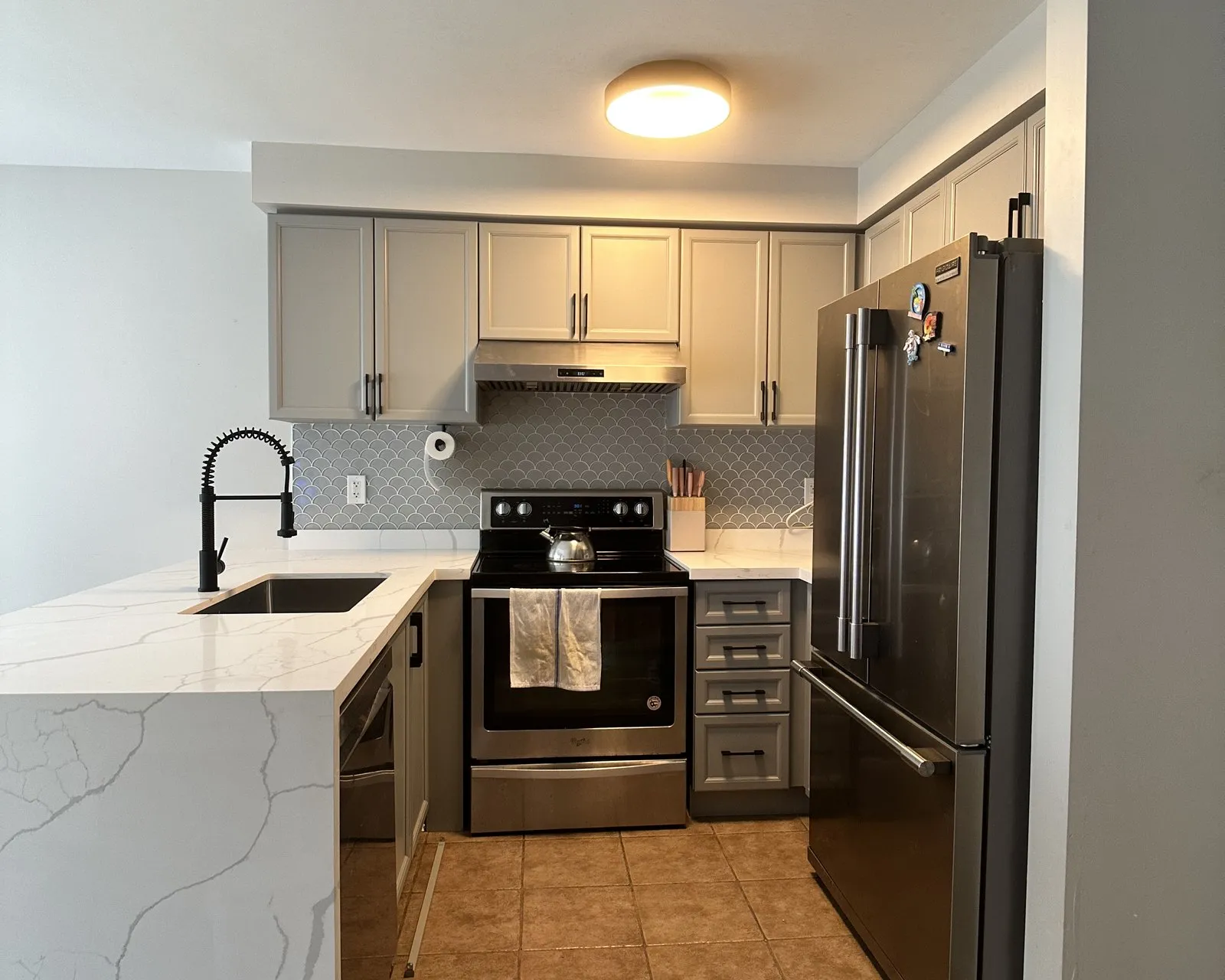 A new white quartz top with a waterfall end, fitted to painted cabinets that stayed exactly where they were