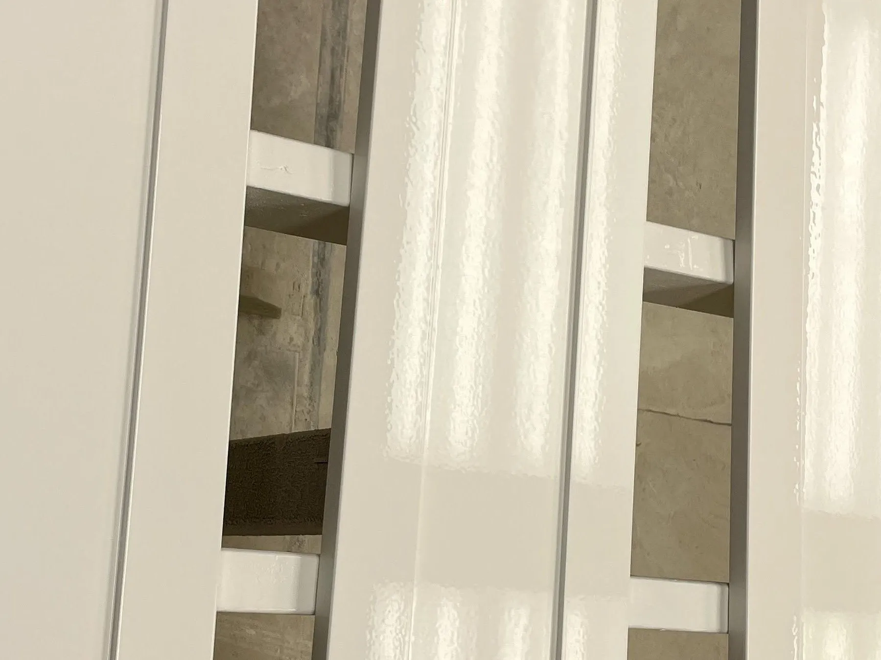 Sprayed white cabinet doors leaning on trestles, the cured 2K catching the light in a long unbroken highlight down each panel