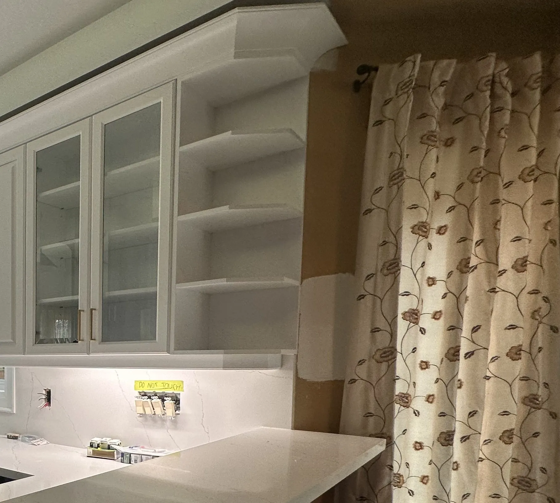 New white upper cabinets with frosted glass doors and brushed brass bar pulls, above a white quartz counter