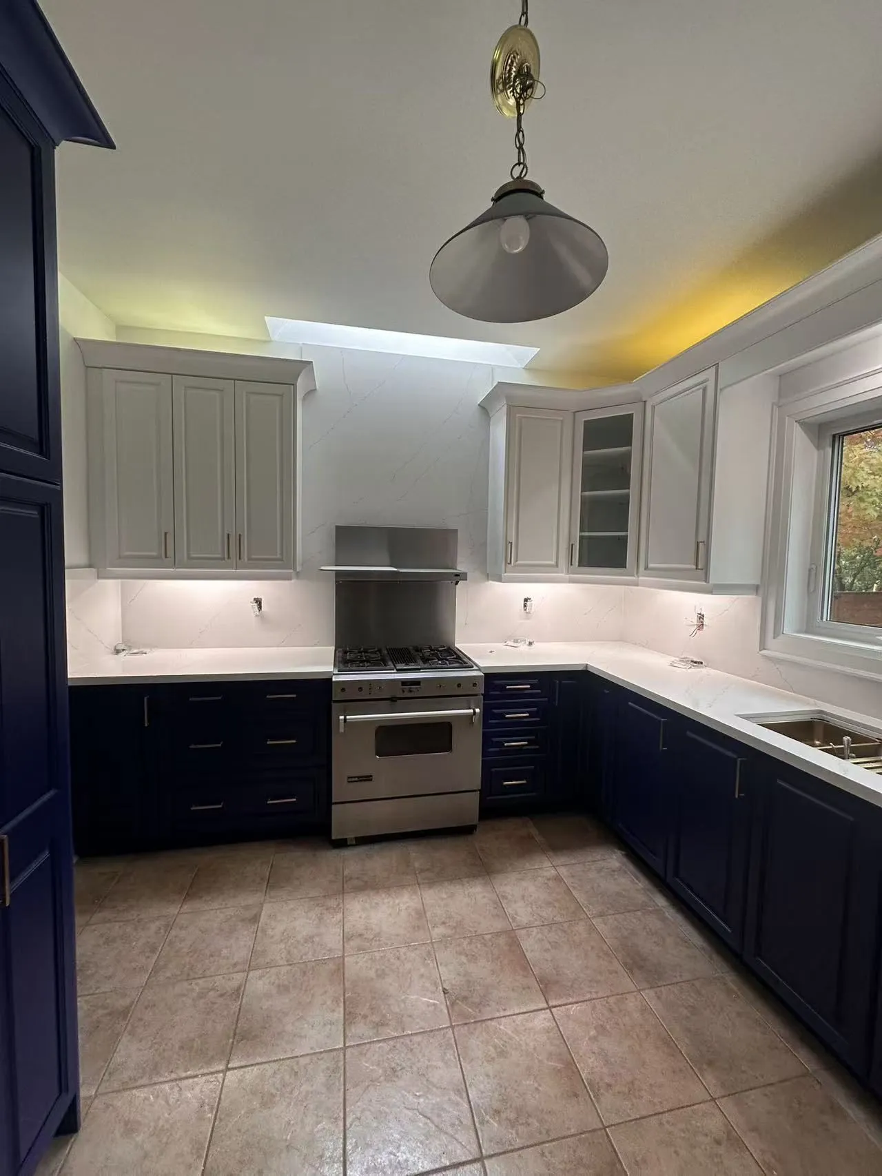 The same wall finished — a new closed cabinet where the wine rack stood, and an open stainless hood where the cabinet above the range used to be