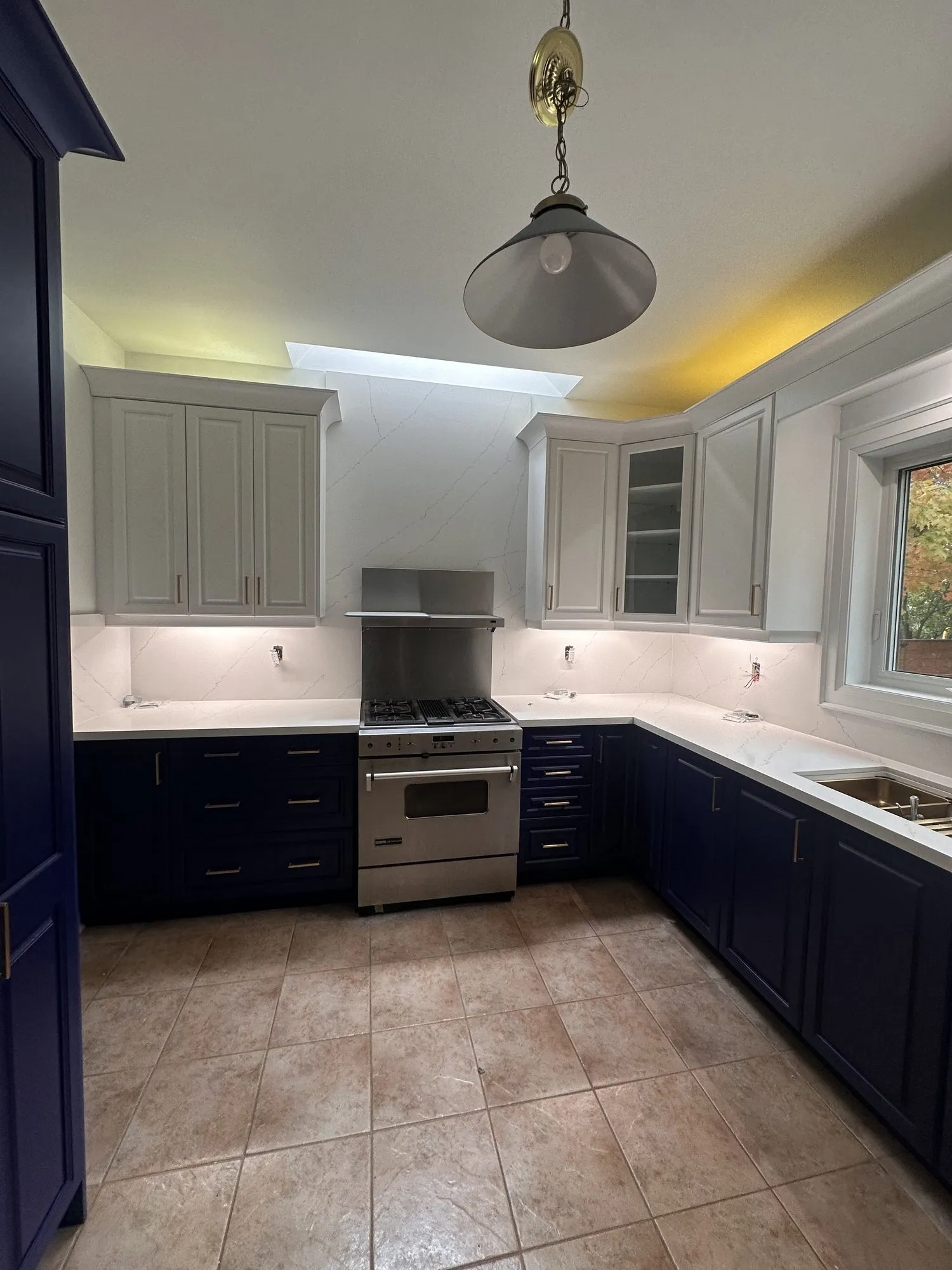 The finished kitchen — Blue Grotto base cabinets and Chantilly Lace uppers, white quartz counters, brushed brass pulls