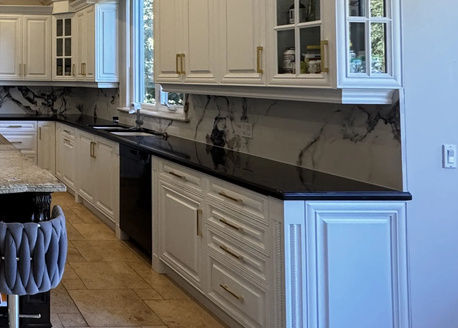 White raised-panel drawers and doors with gold bar pulls under a black countertop