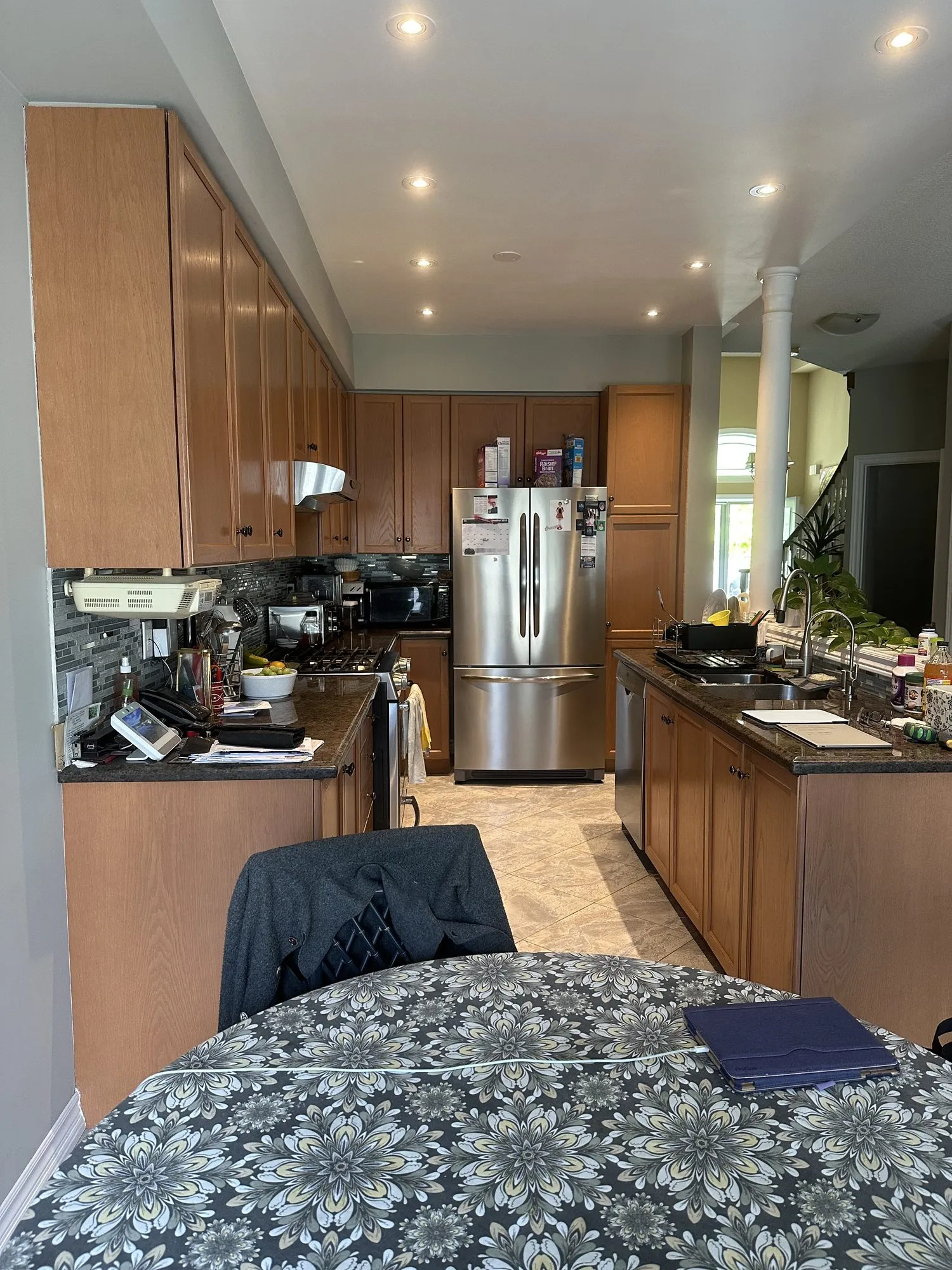 The kitchen before — mid-brown oak doors, dark speckled granite counters and a dark tiled backsplash