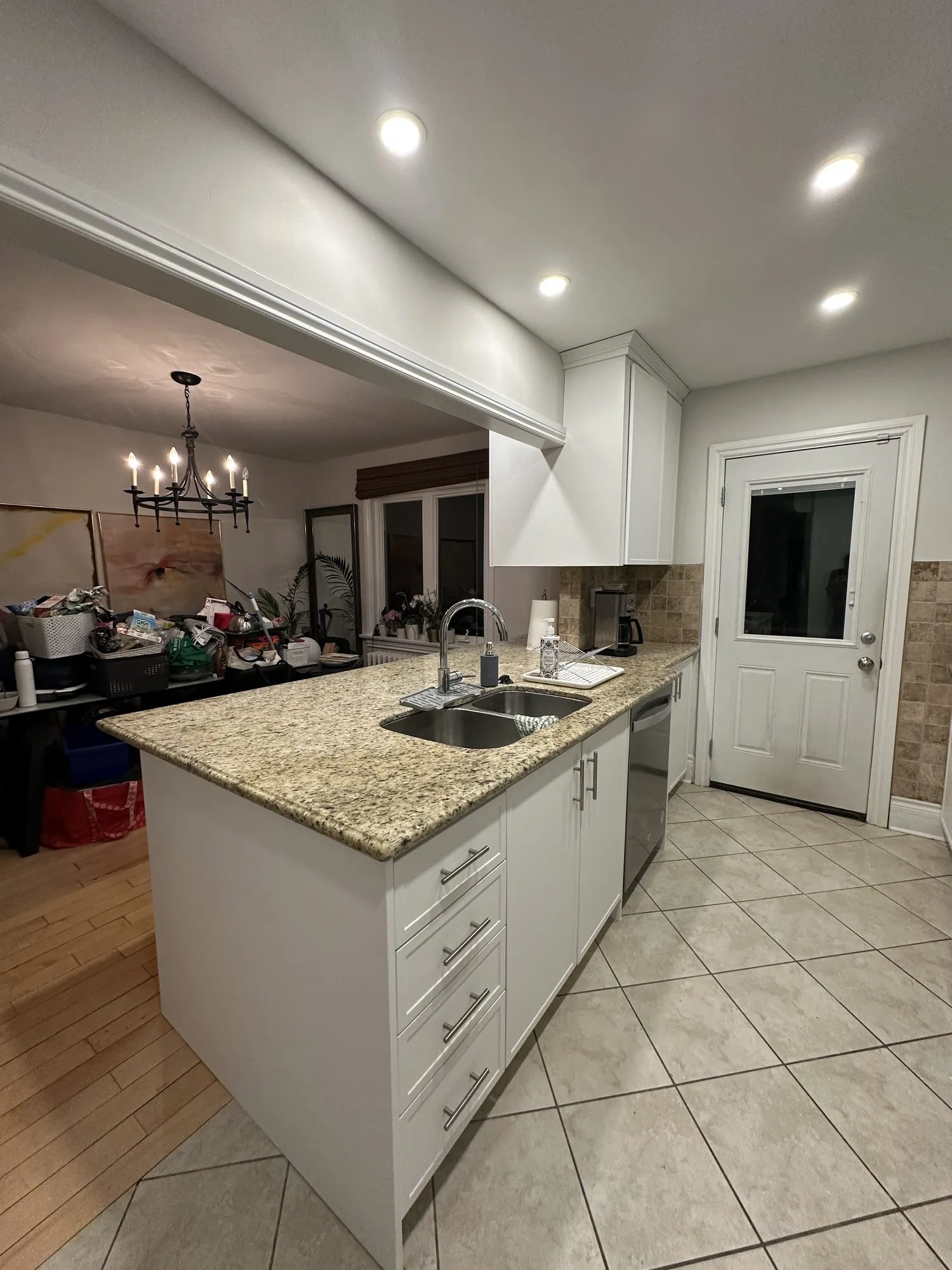 The finished kitchen — white doors throughout, the same granite counters and the same tiled floor as before