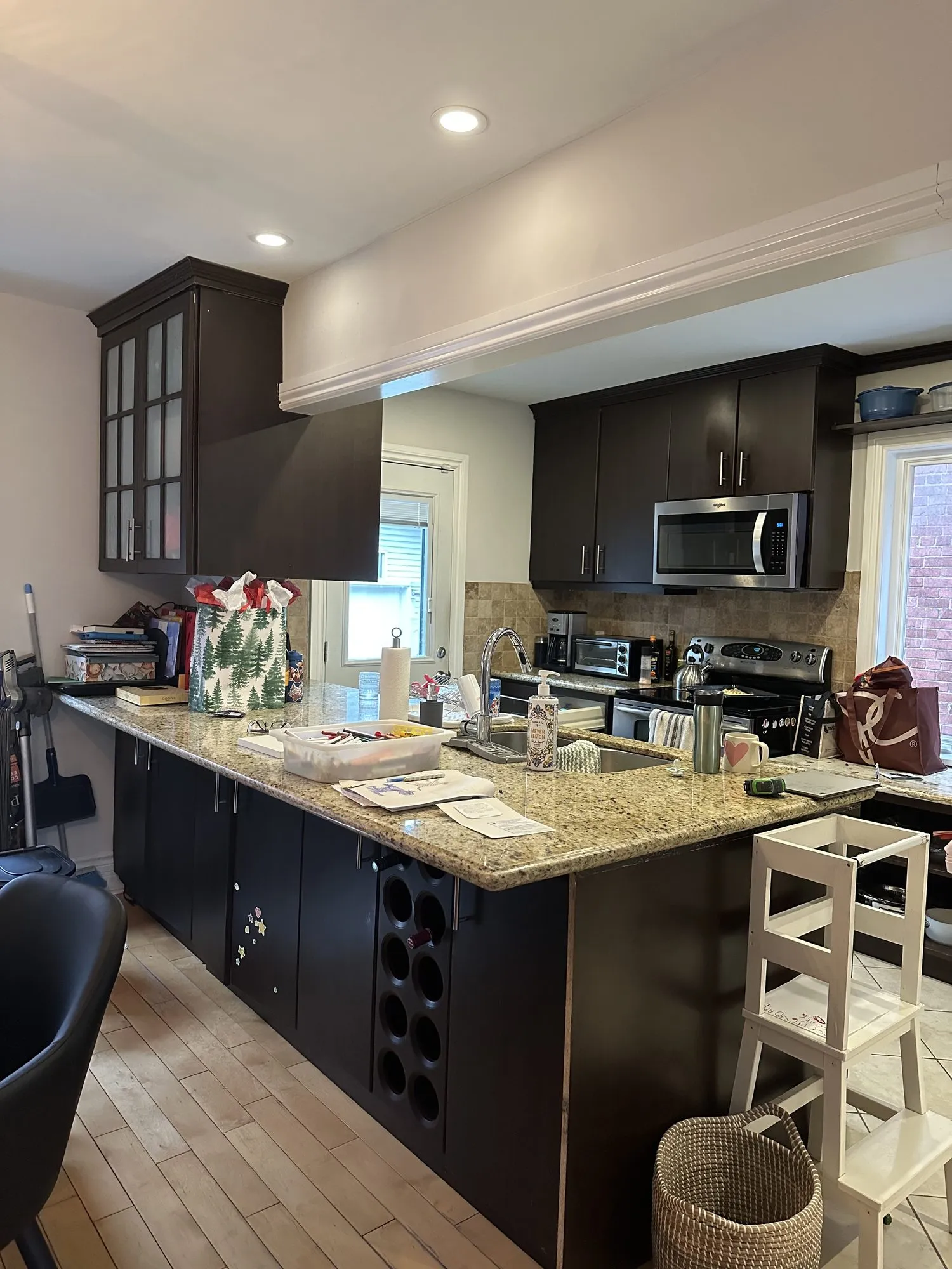 The kitchen before — espresso cabinets with a built-in wine rack at the end of the island, speckled granite counters and a tiled floor