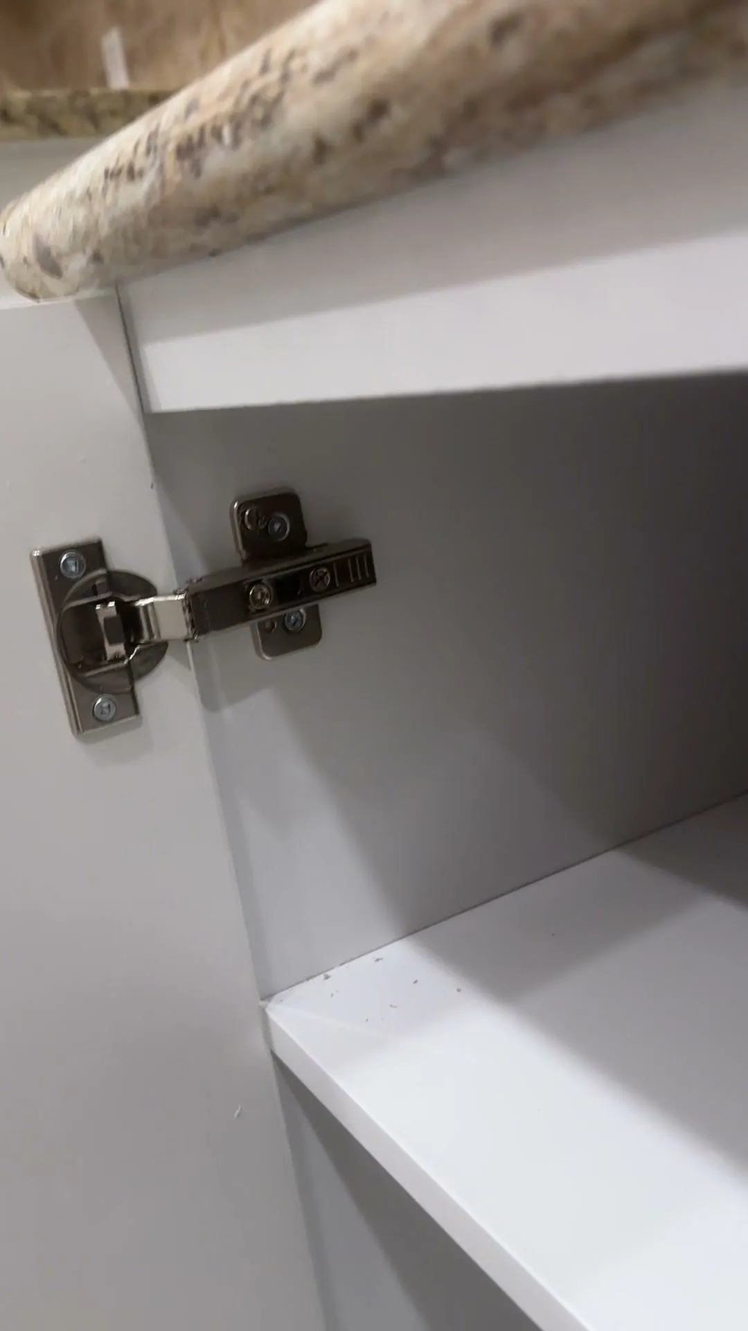 A new white door open on its concealed hinge, showing the original white cabinet box behind it and the granite counter above