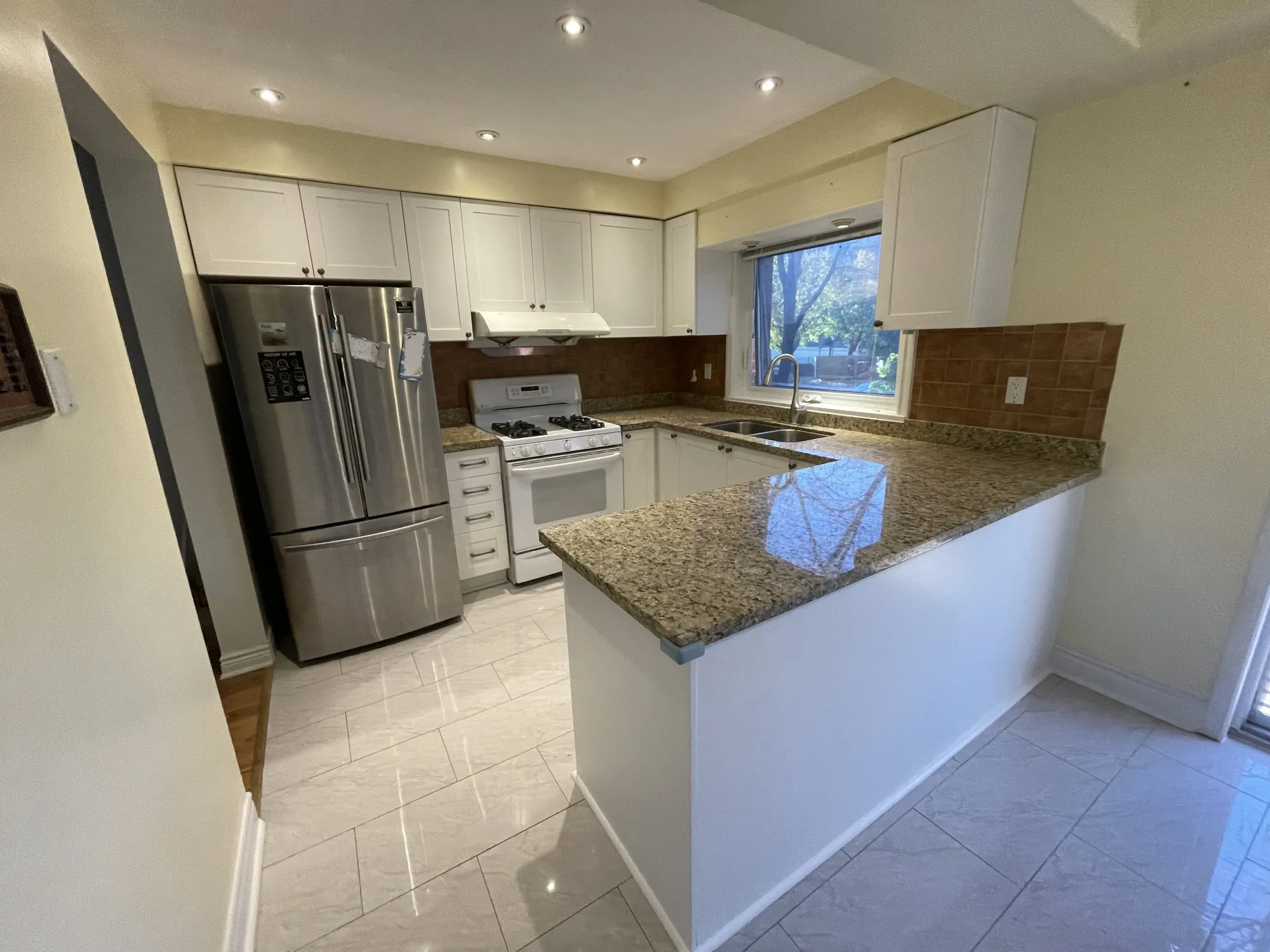 The finished peninsula with new white shaker drawer fronts and bar handles under the original granite counter