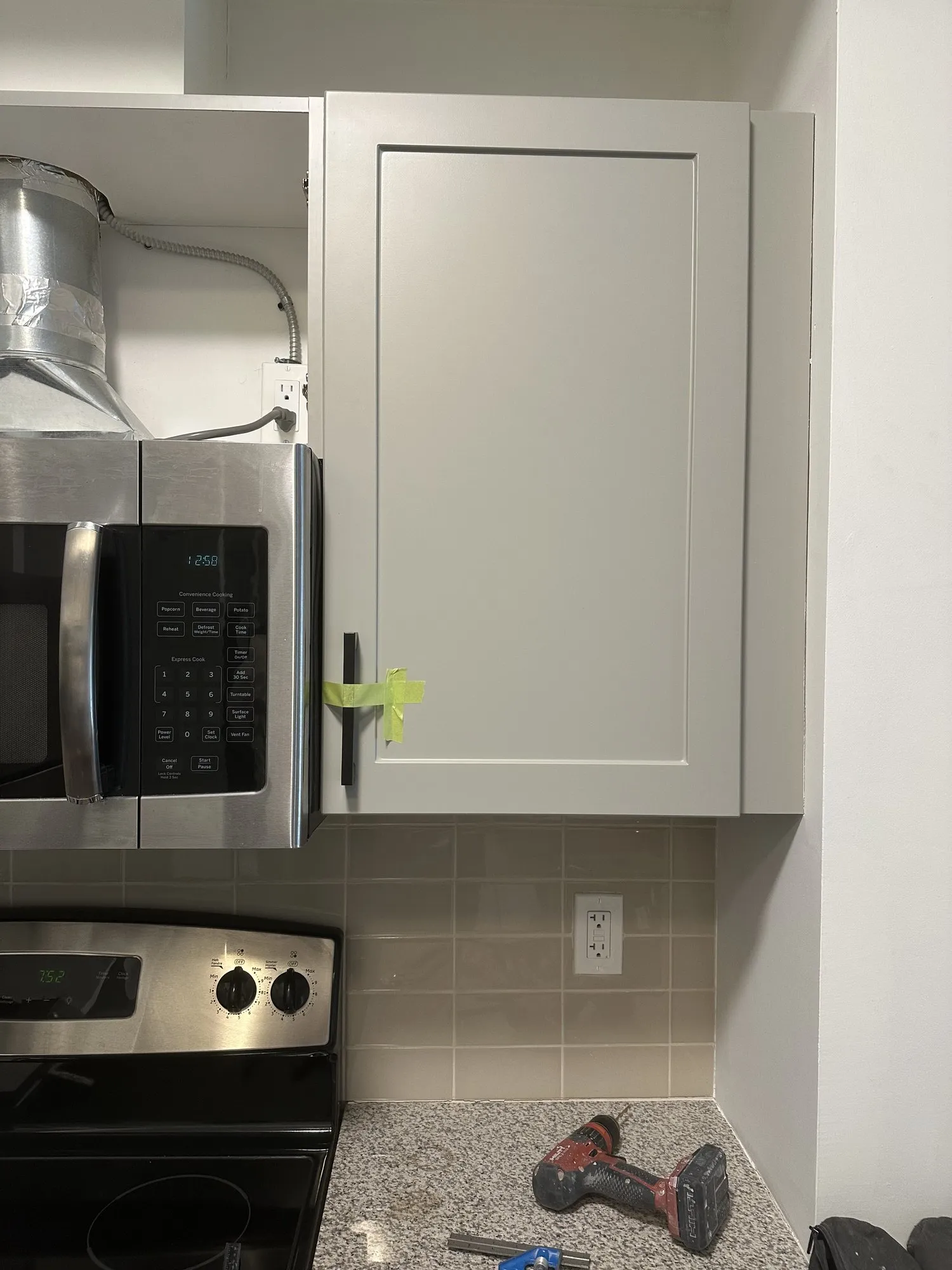 The first grey shaker door hung on an upper cabinet beside the remaining dark espresso doors, both finishes in one frame