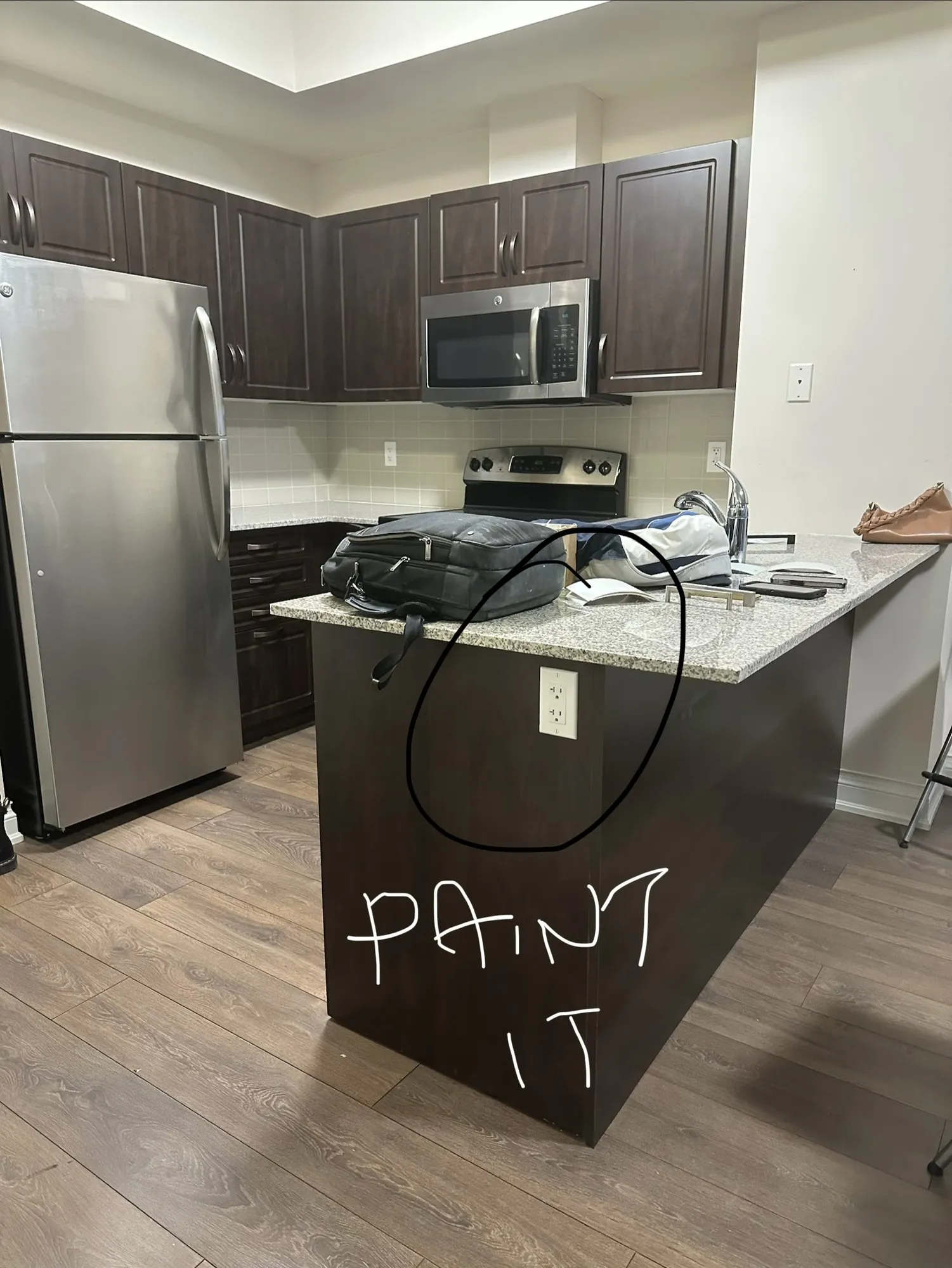 The kitchen before work started with PAINT IT written by hand and circled on the end panel of the peninsula