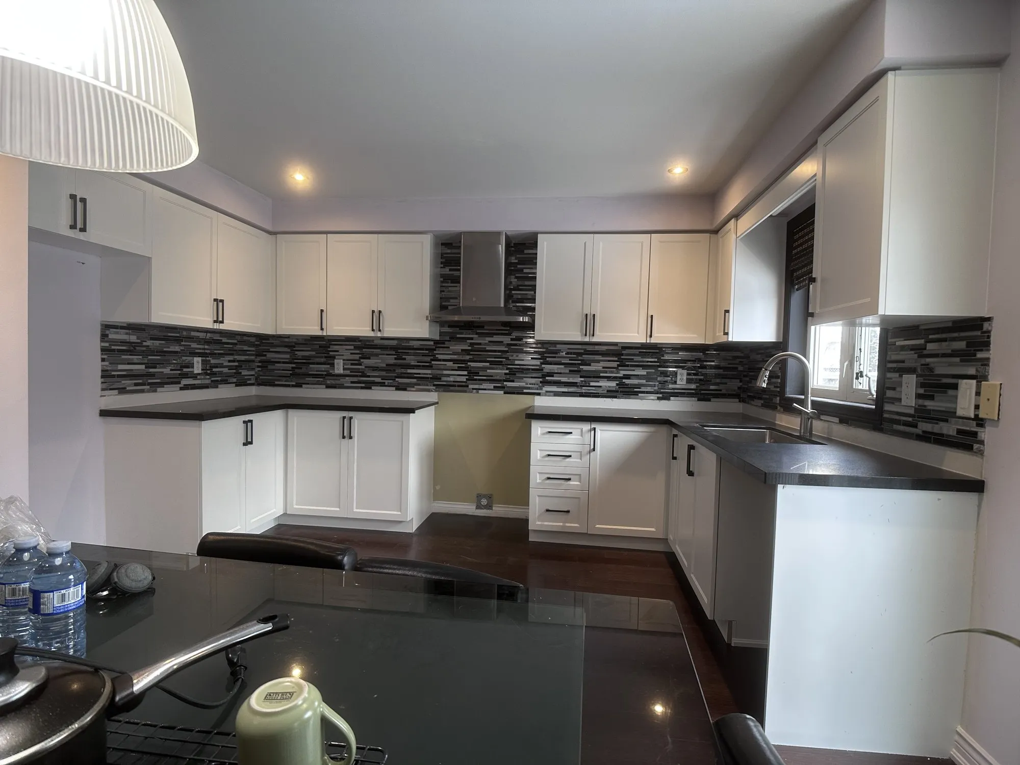 The finished kitchen with new white doors around the U-shaped run, the dark counters and mosaic backsplash kept