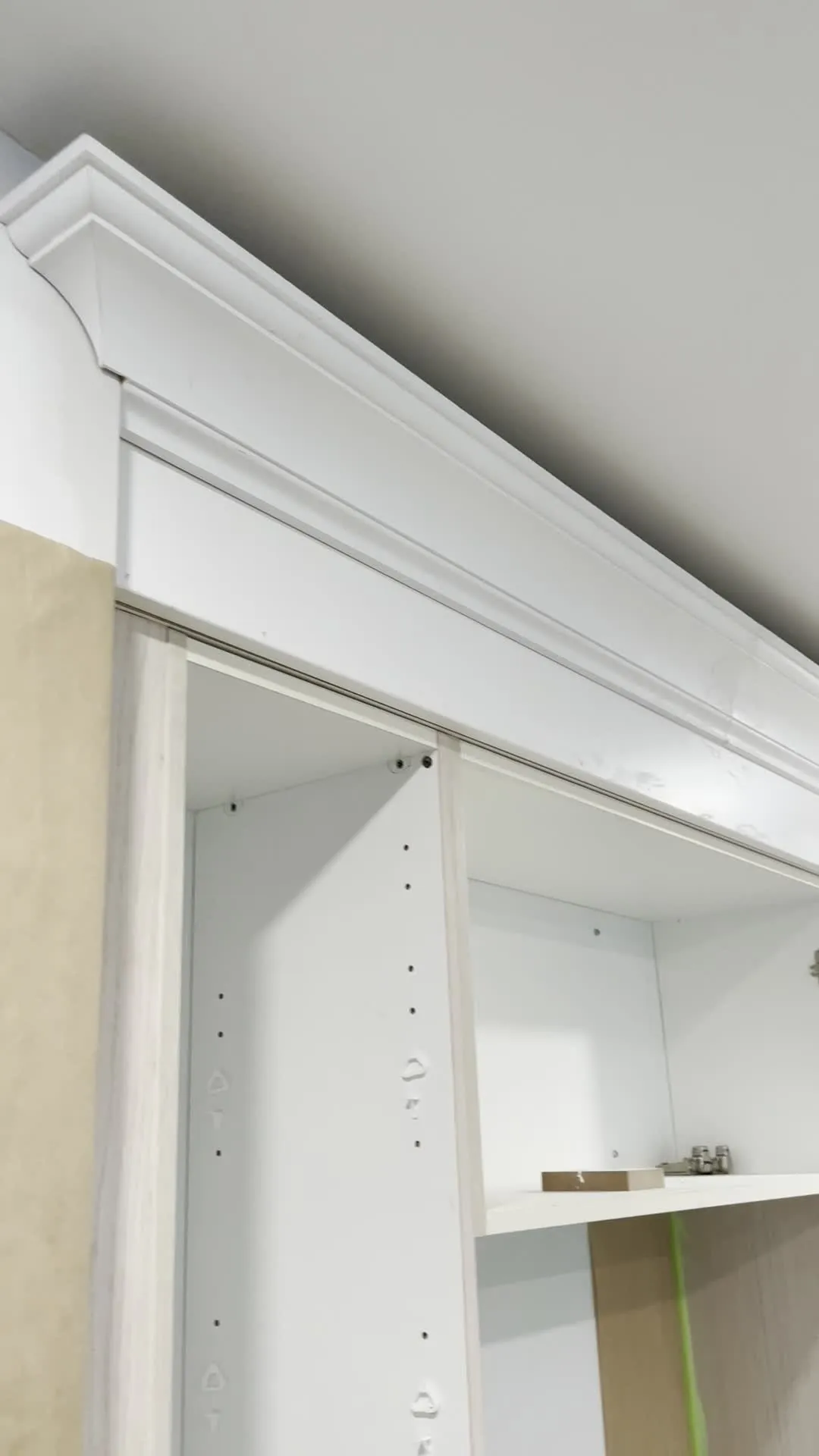 New white crown moulding fitted along the ceiling above a cabinet frame whose stiles are still the original unpainted pale oak