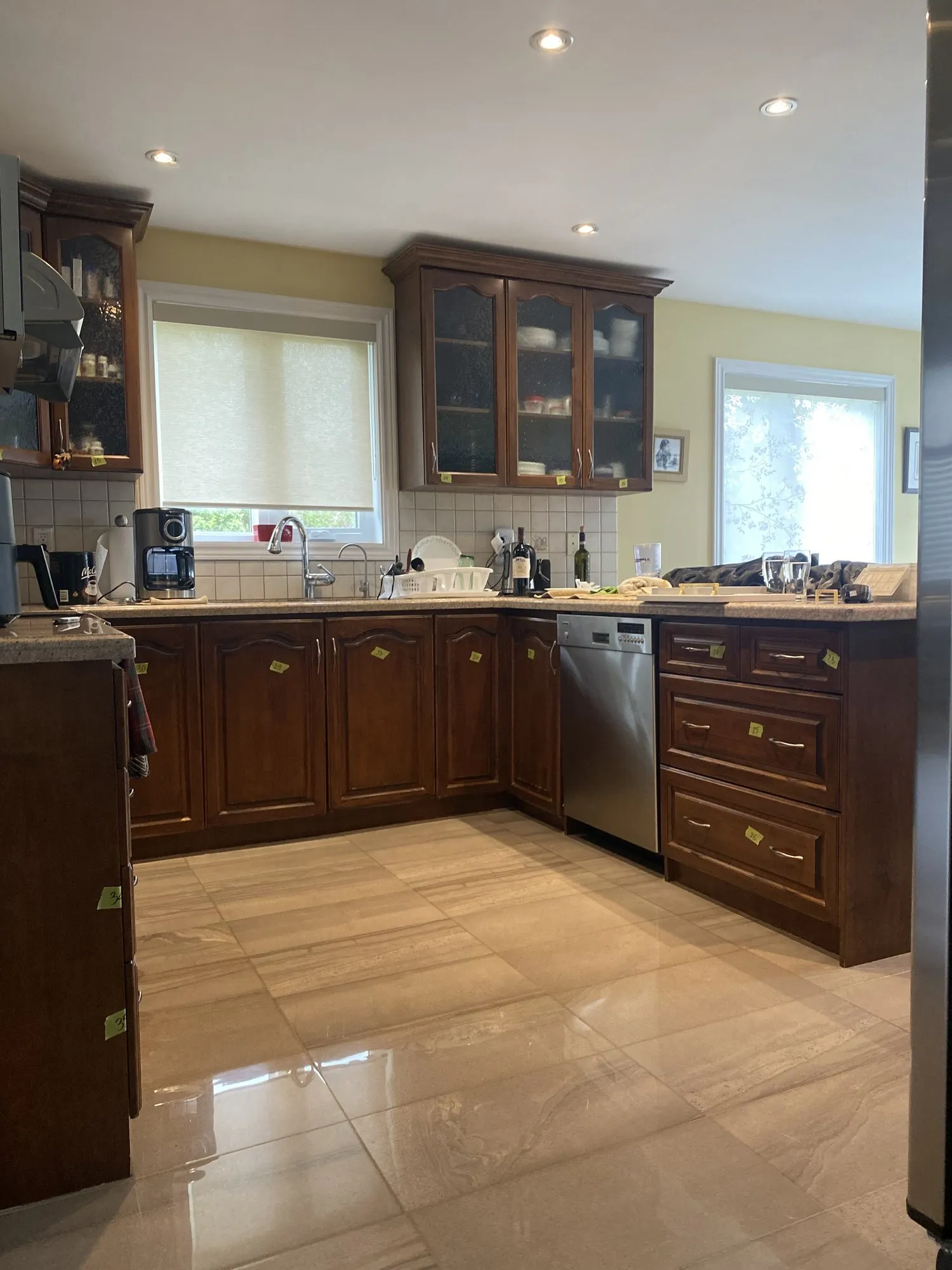 The original dark walnut kitchen with glass-fronted upper cabinets either side of the window, everything inside them on display