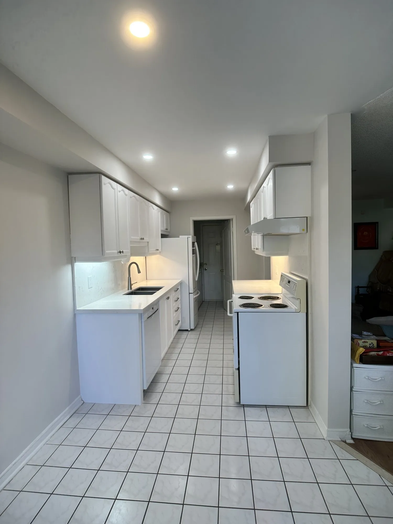 The finished galley in white, the run closed along its whole length, with a valance carrying light under the upper cabinets