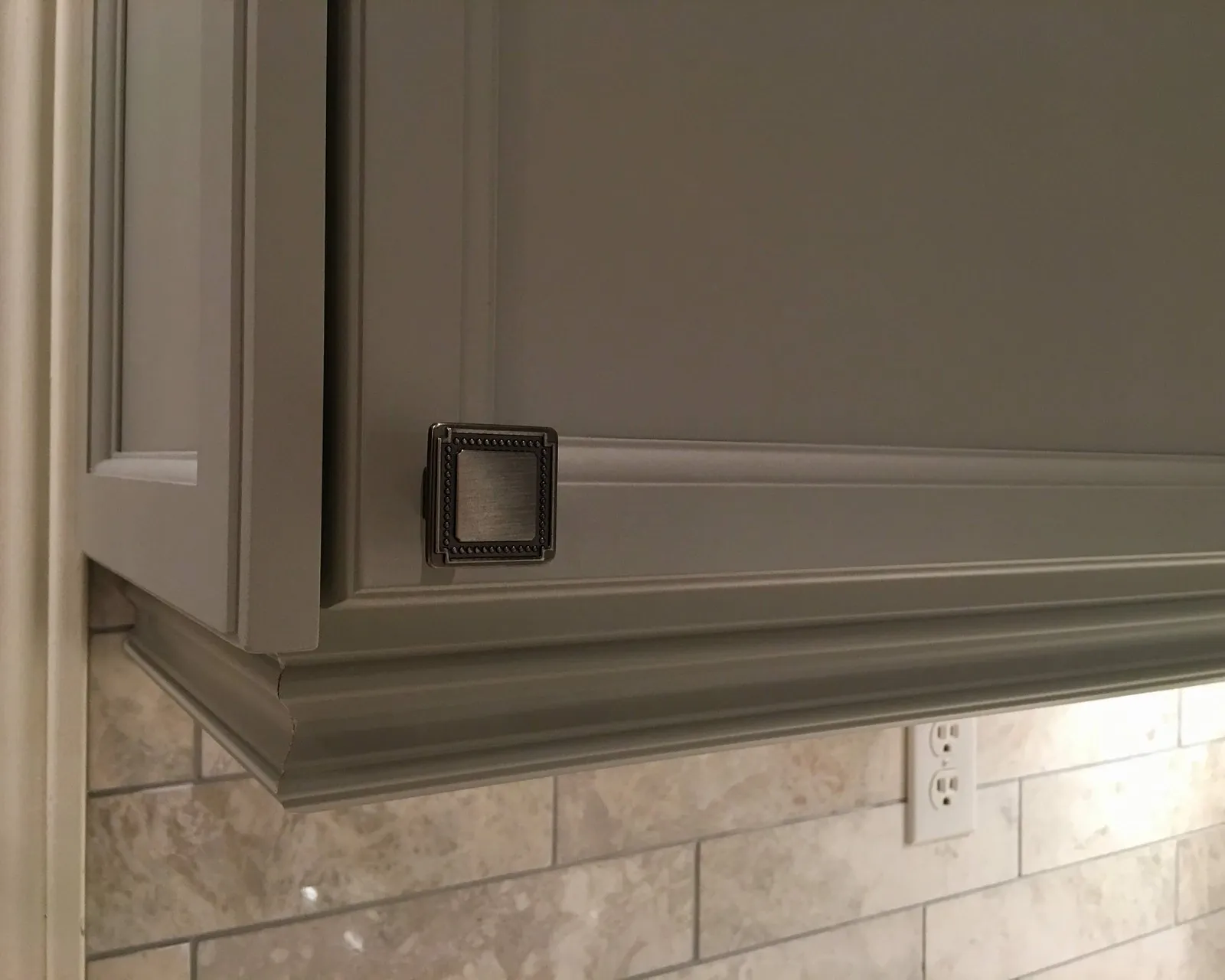 A painted cabinet door and its applied moulding at close range, the finish unbroken across the profile and the flat
