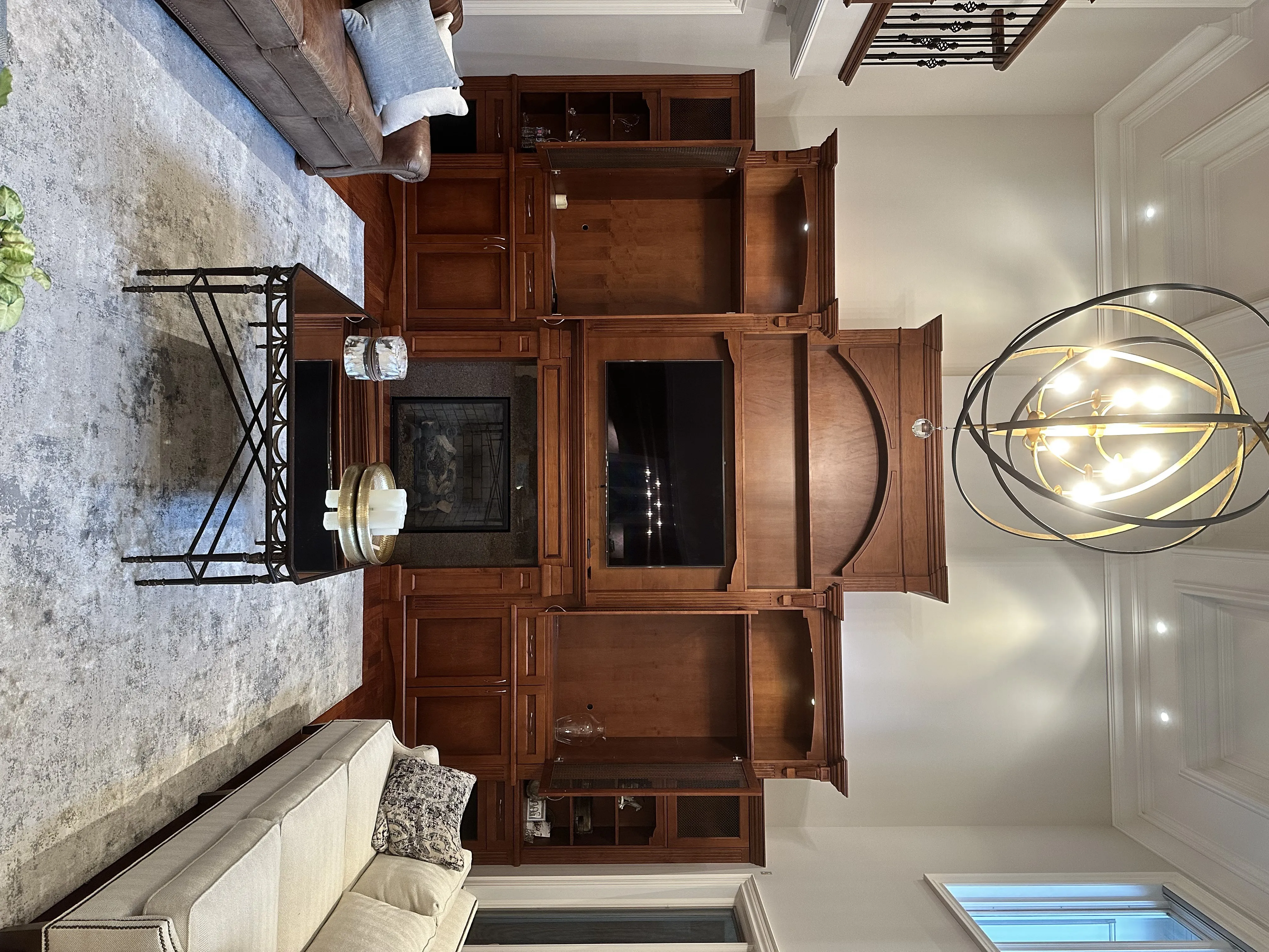 An ornate stained wood entertainment built-in around a fireplace, the arched pediment and crown detail reading clearly through a warm cherry stain