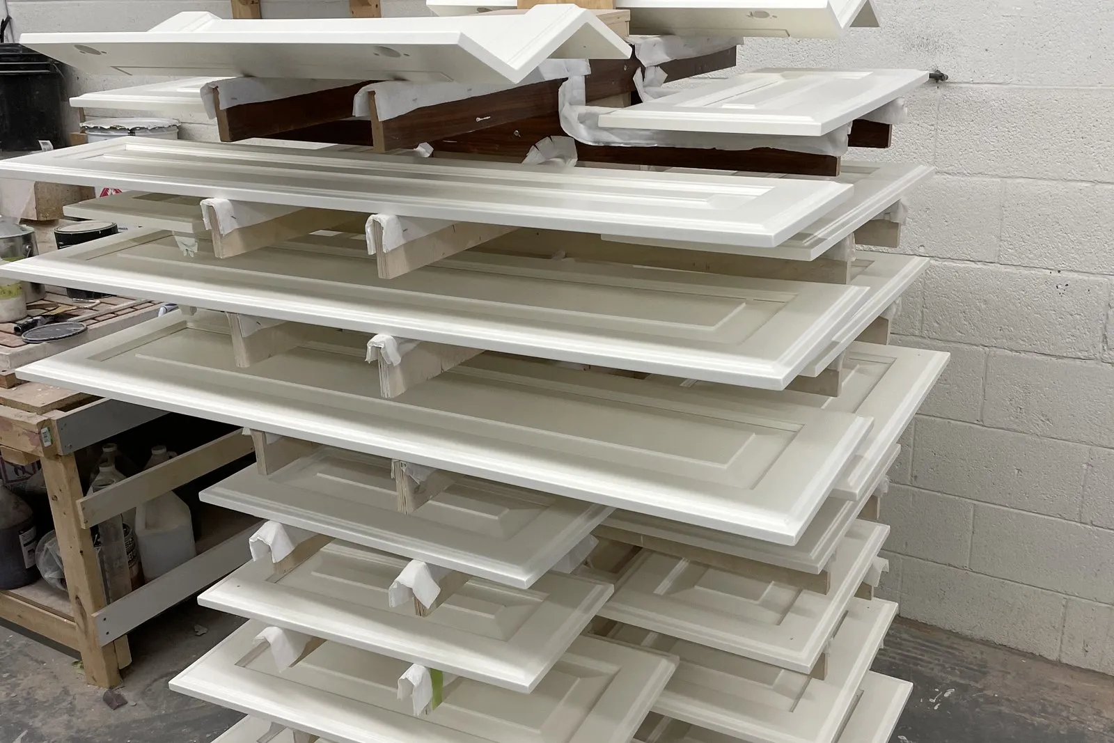 Freshly sprayed cabinet doors racked in the shop, stacked on spacers while the finish cures