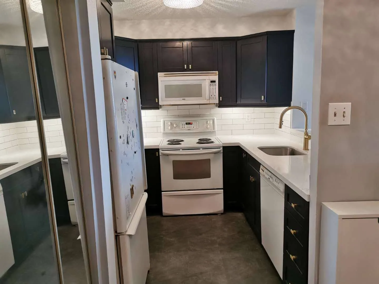 A kitchen sprayed a confident navy blue below and white above, gold hardware and a quartz counter