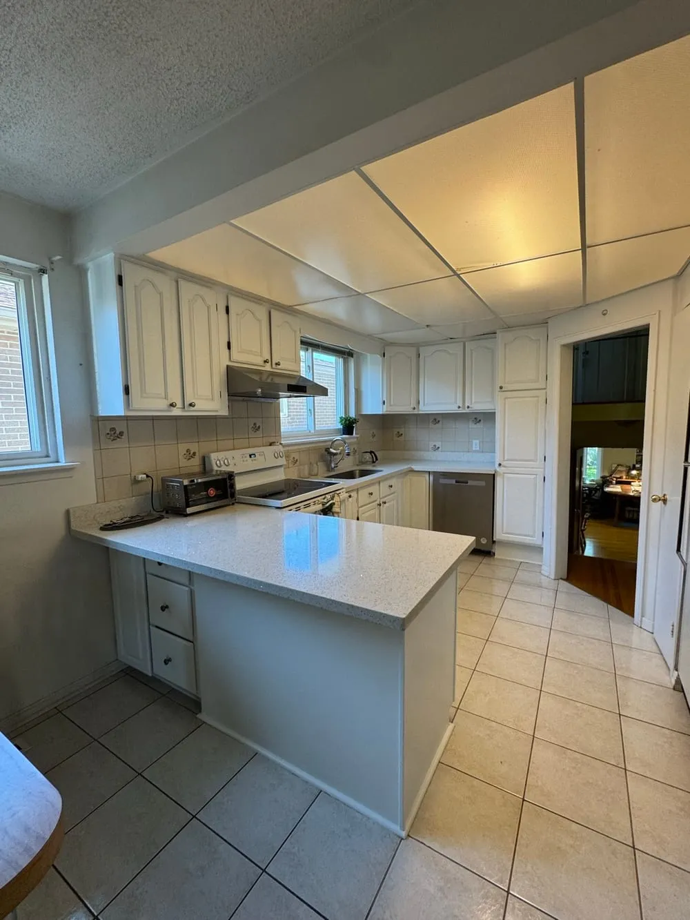 A photograph of the same kitchen after the cabinets were sprayed white