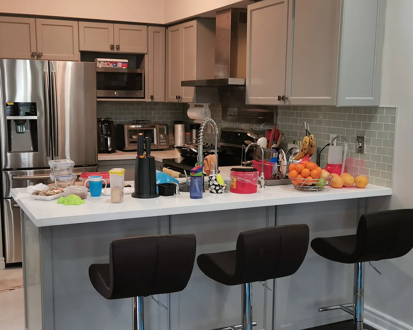 After — A kitchen before and after — dark laminate tops on oak cabinets replaced with white quartz, on cabinets refinished in grey at the same time