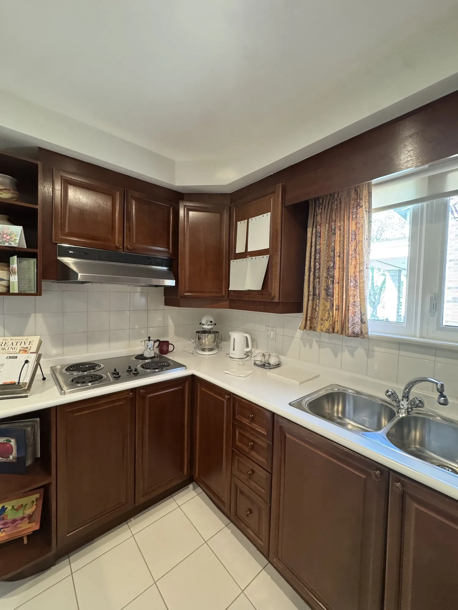 The kitchen before the work, dark walnut raised-panel cabinetry with a blind corner beside the stove and an open shelf unit at the end of the run