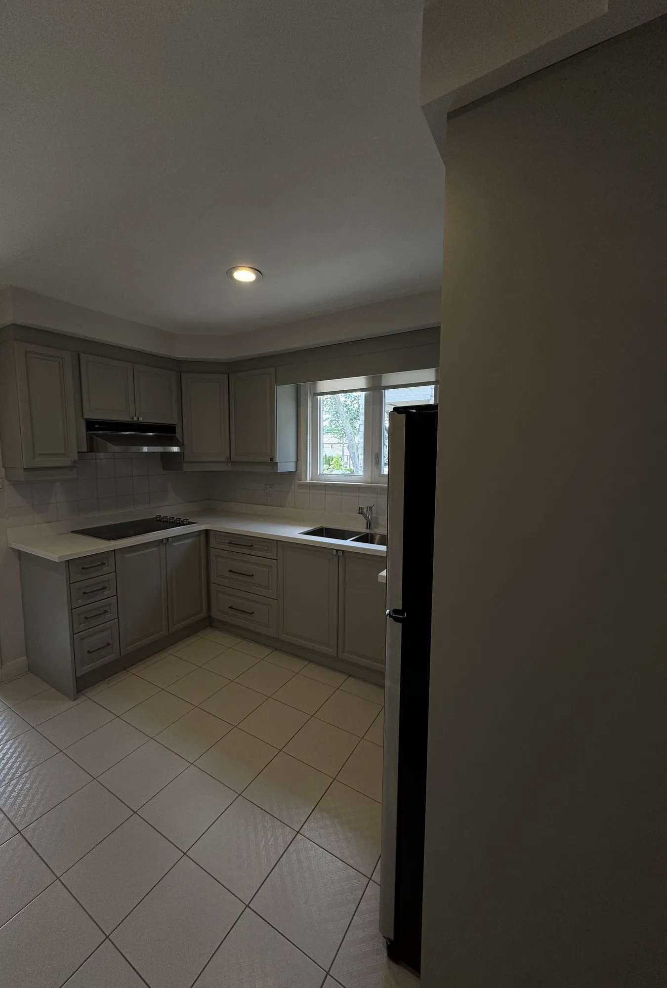 The finished kitchen sprayed a single grey tone, new drawer banks where the corner cabinets were, the tile floor and layout unchanged