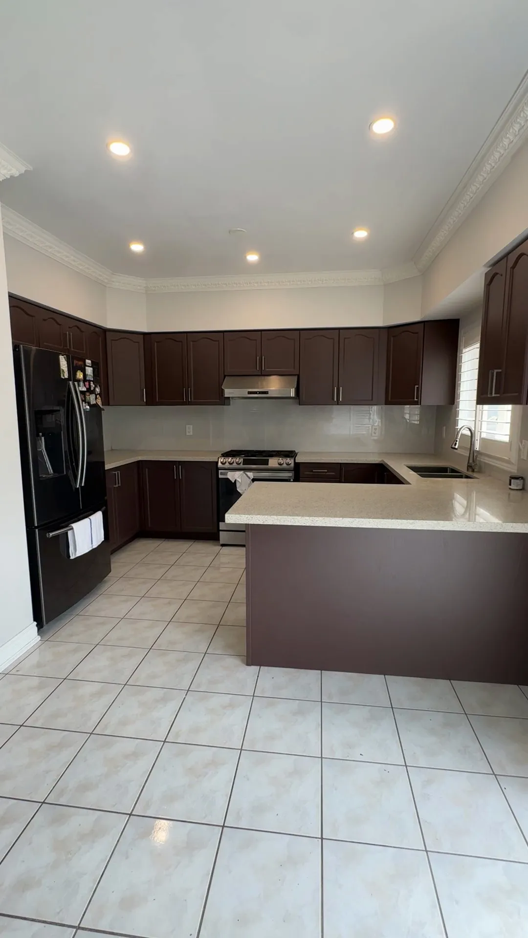 The finished Rouge kitchen — honey oak cabinetry sprayed a deep warm brown, the original quartz counters, tile backsplash and tile floor all kept