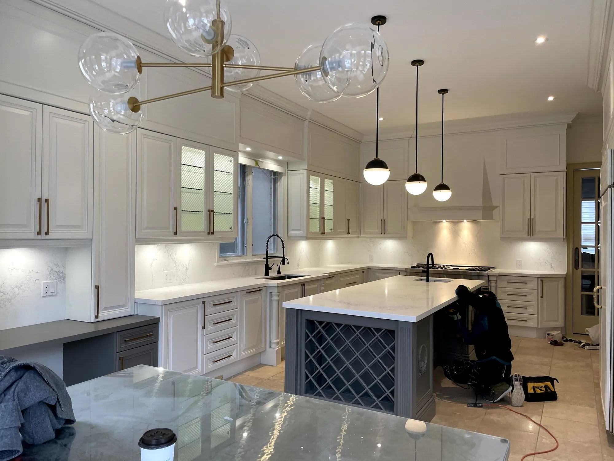 The finished kitchen with Simply White cabinetry, a Chelsea Grey island, glazed upper doors and black pendants over white counters