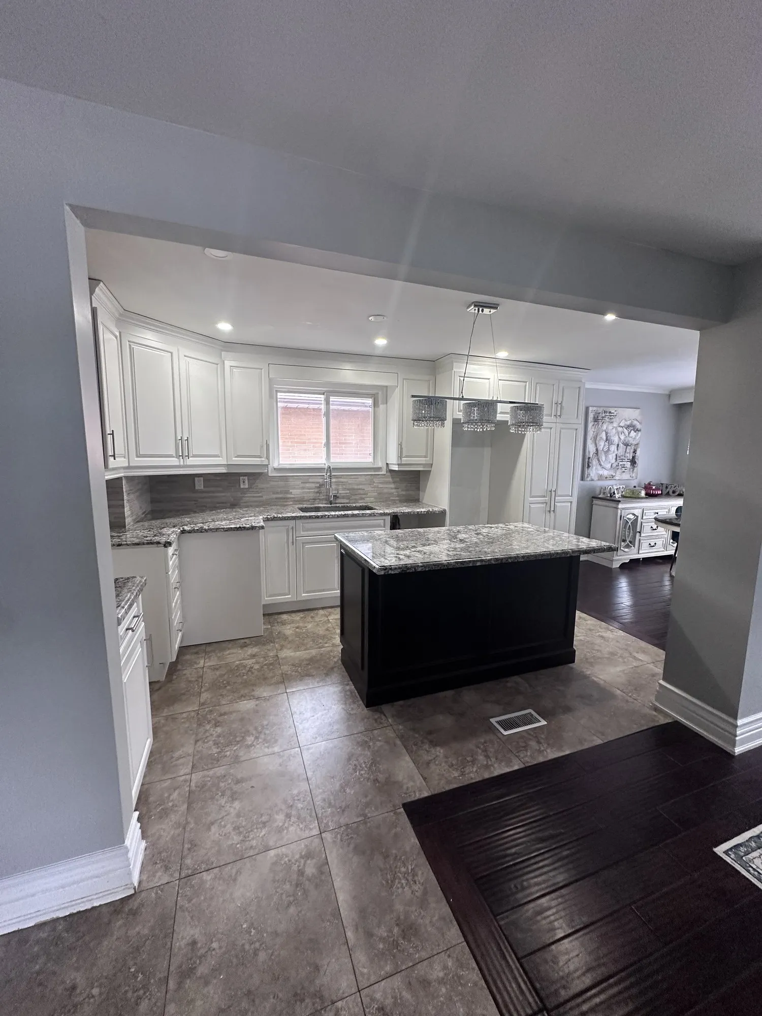 The finished kitchen with a white perimeter and the original espresso island standing in the middle of it