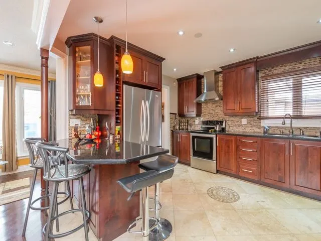 A rich cherry-stained kitchen with a wine rack cabinet and stone-look backsplash, the wood grain reading clearly through the finish