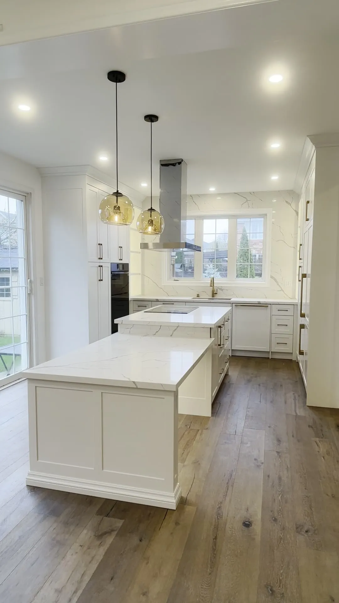 A finished custom kitchen in Toronto — white shaker cabinetry, a waterfall marble-look island and a stainless hood, walked through room by room